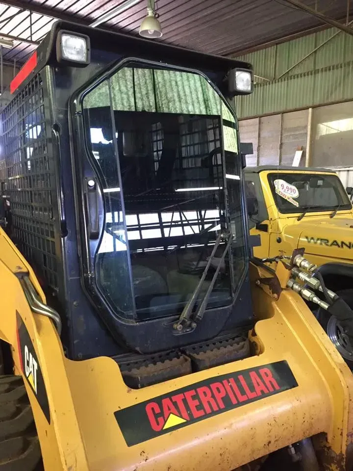 A Caterpillar Tractor Is Parked In A Warehouse Next To A Yellow Jeep — Petrena Windscreens In Leyburn, QLD