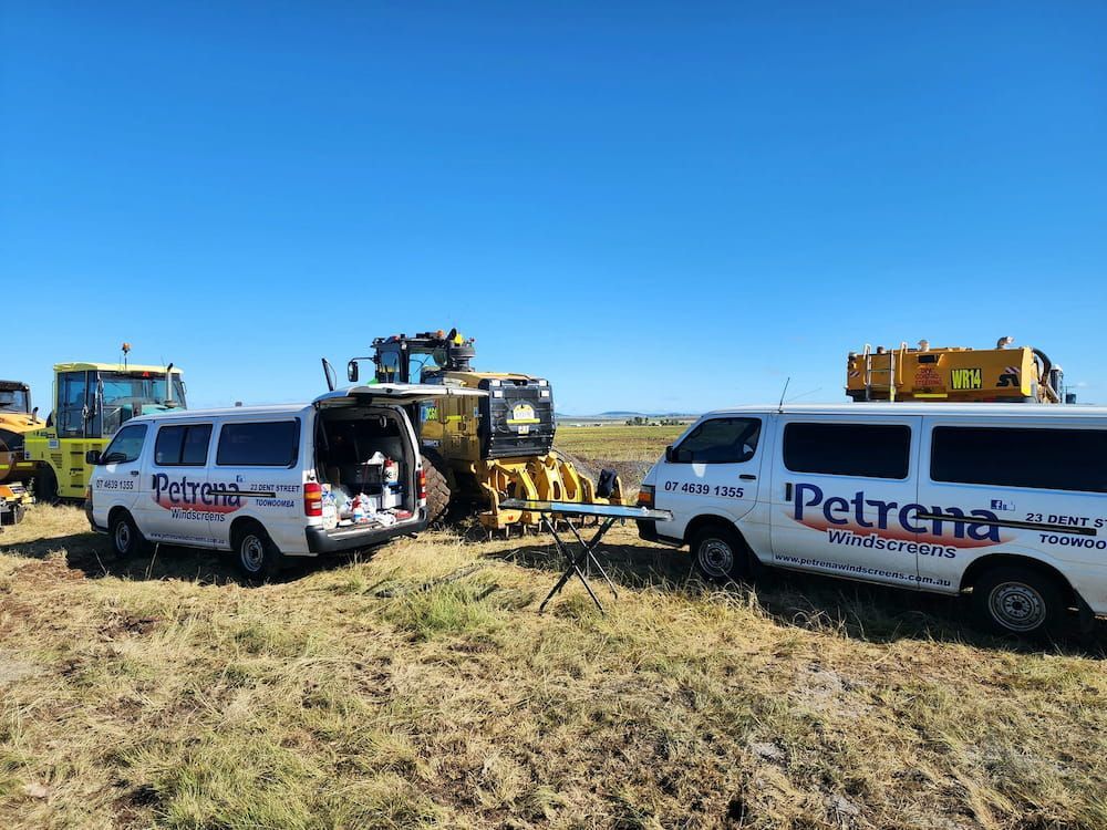 Two Vans Are Parked In A Field Next To A Tractor — Petrena Windscreens In Millmerran, QLD