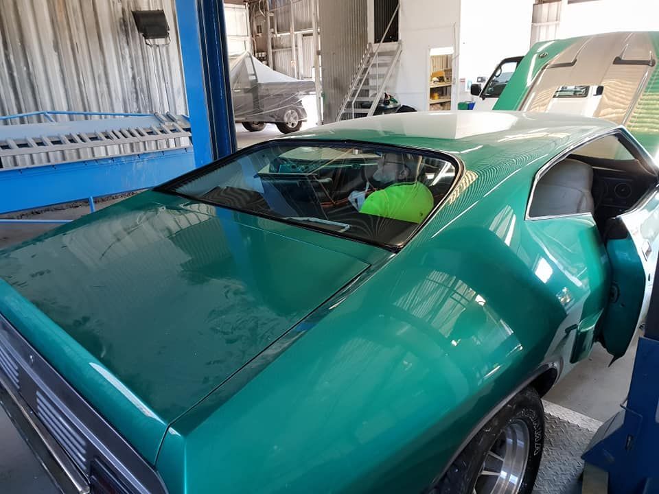 A Green Car Is Parked In A Garage With The Door Open — Petrena Windscreens In Gatton, QLD