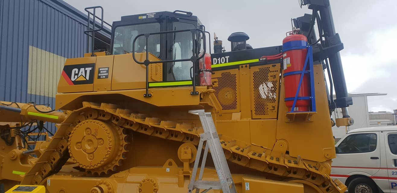 A Large Yellow Bulldozer Is Parked In Front Of A Building — Petrena Windscreens In Toowoomba City, QLD