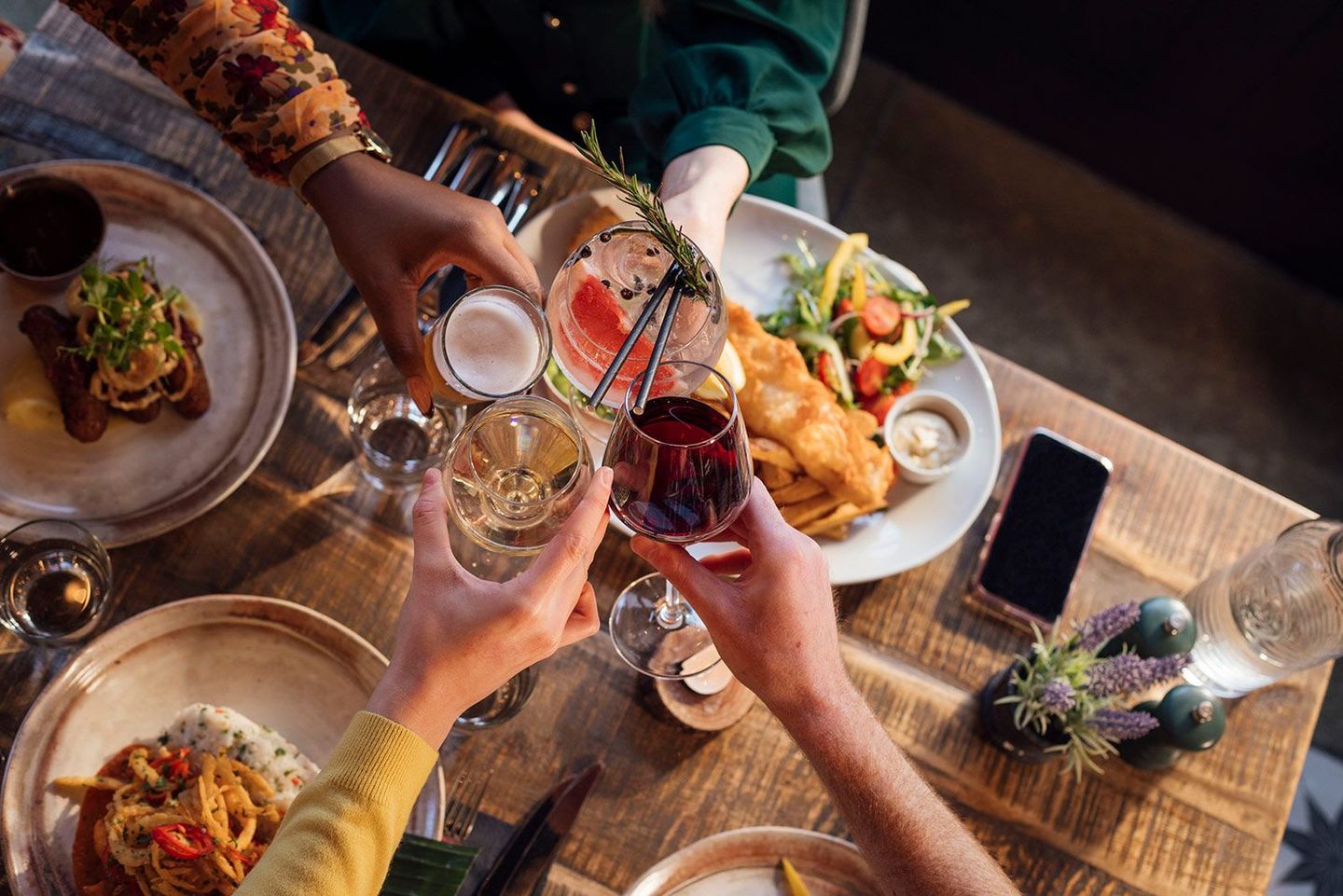 A group of people are sitting at a table eating food and drinking wine.