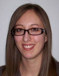 Woman in glasses, against a light background.