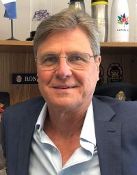 Man with glasses smiles indoors; office setting.