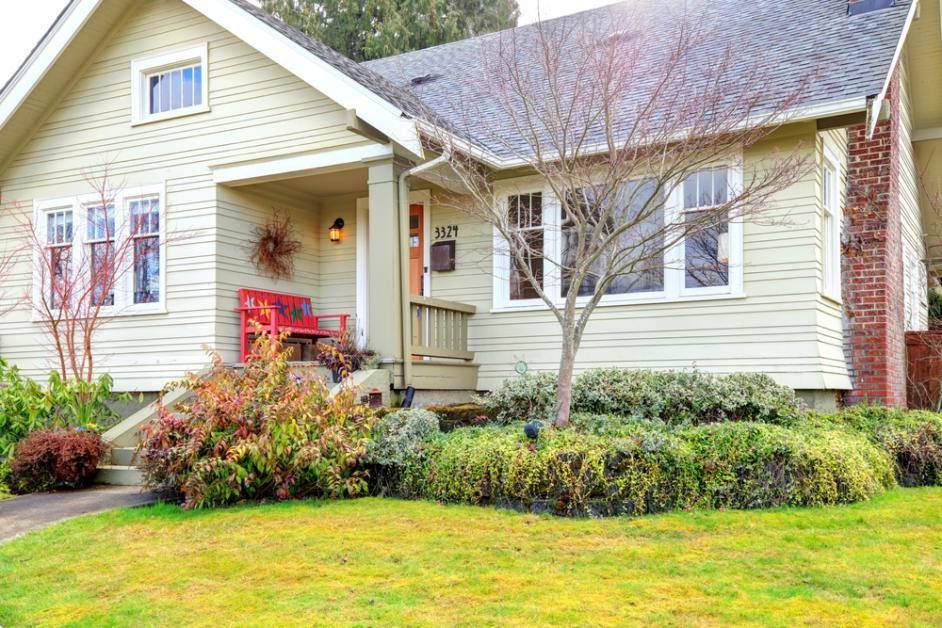 A small house with a lush green lawn in front of it.