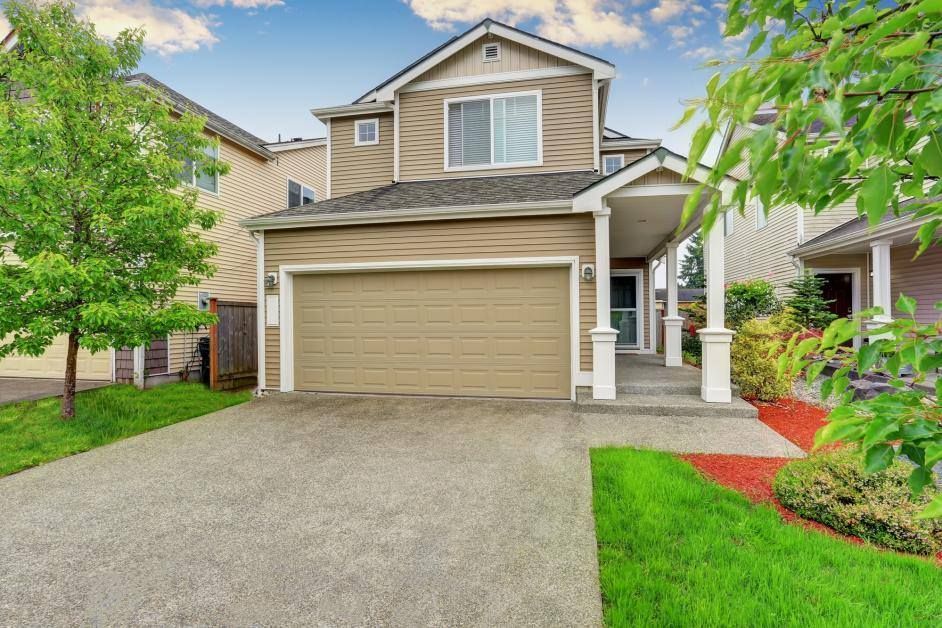 A house with a garage door and a driveway in front of it.