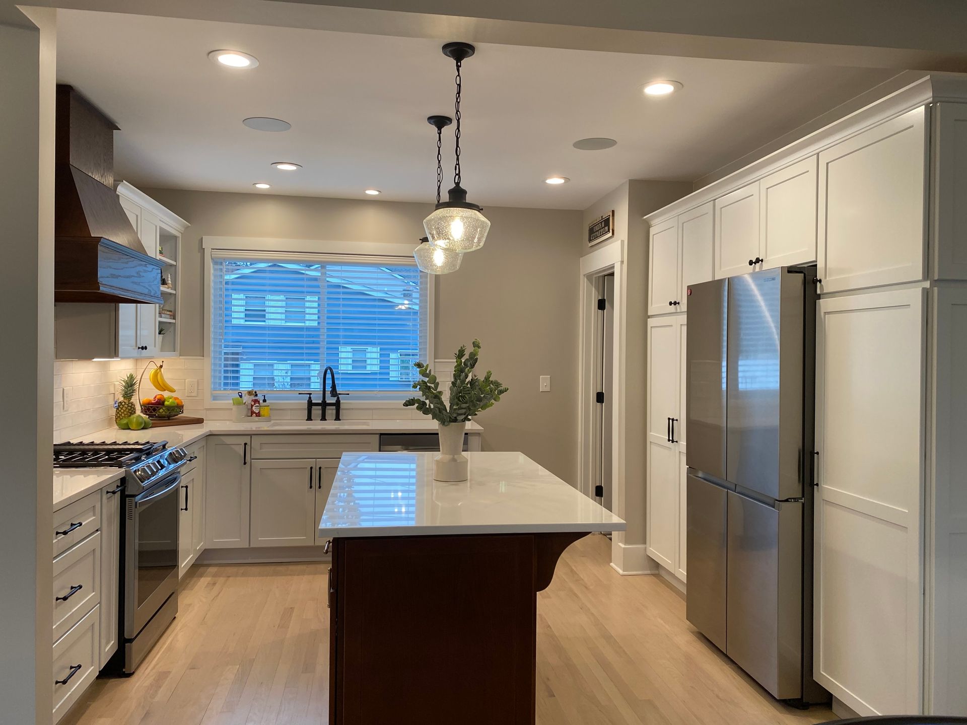 A kitchen with white cabinets , stainless steel appliances , and a large island.