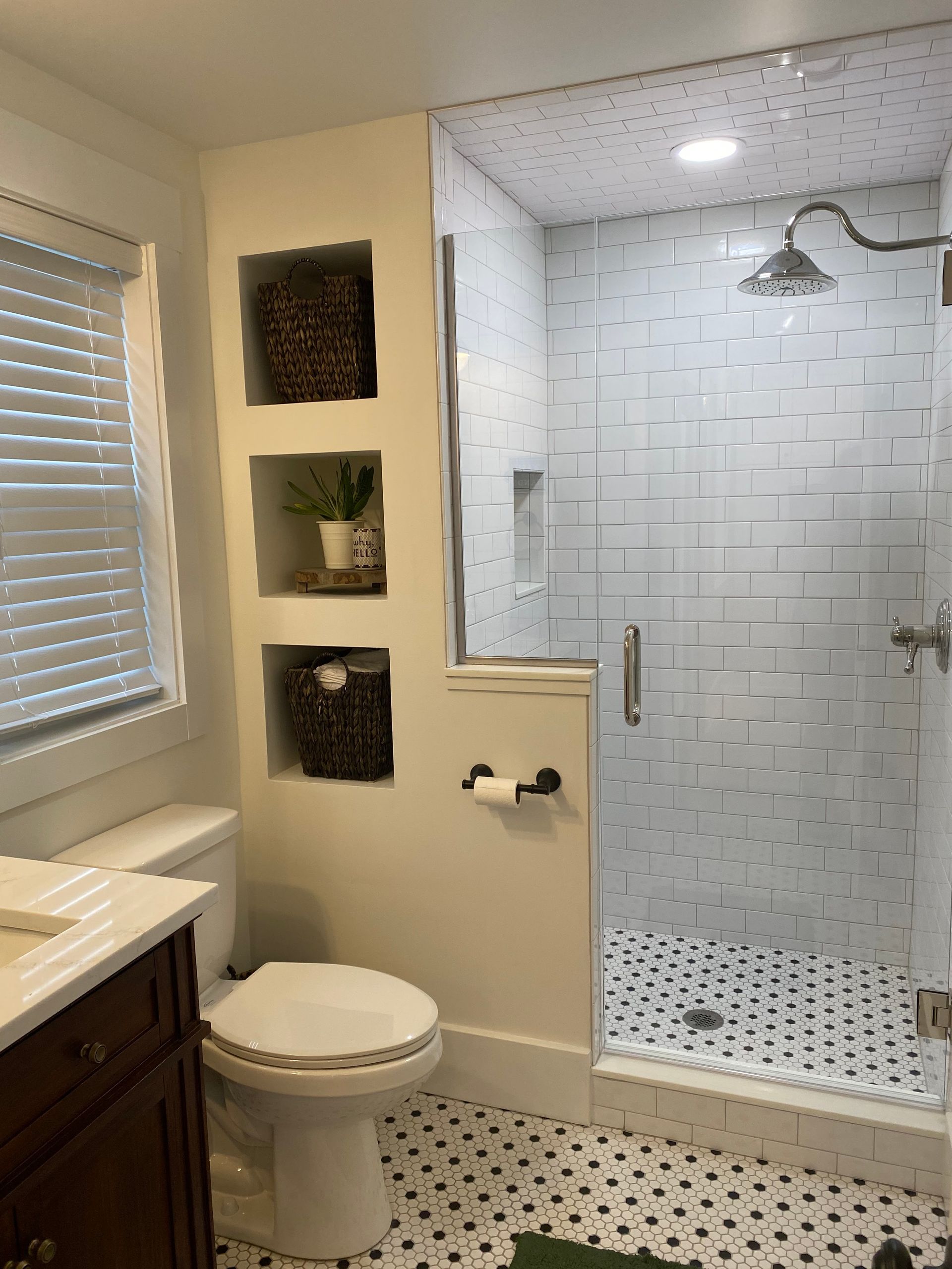 A bathroom with a toilet , sink , shower and window.