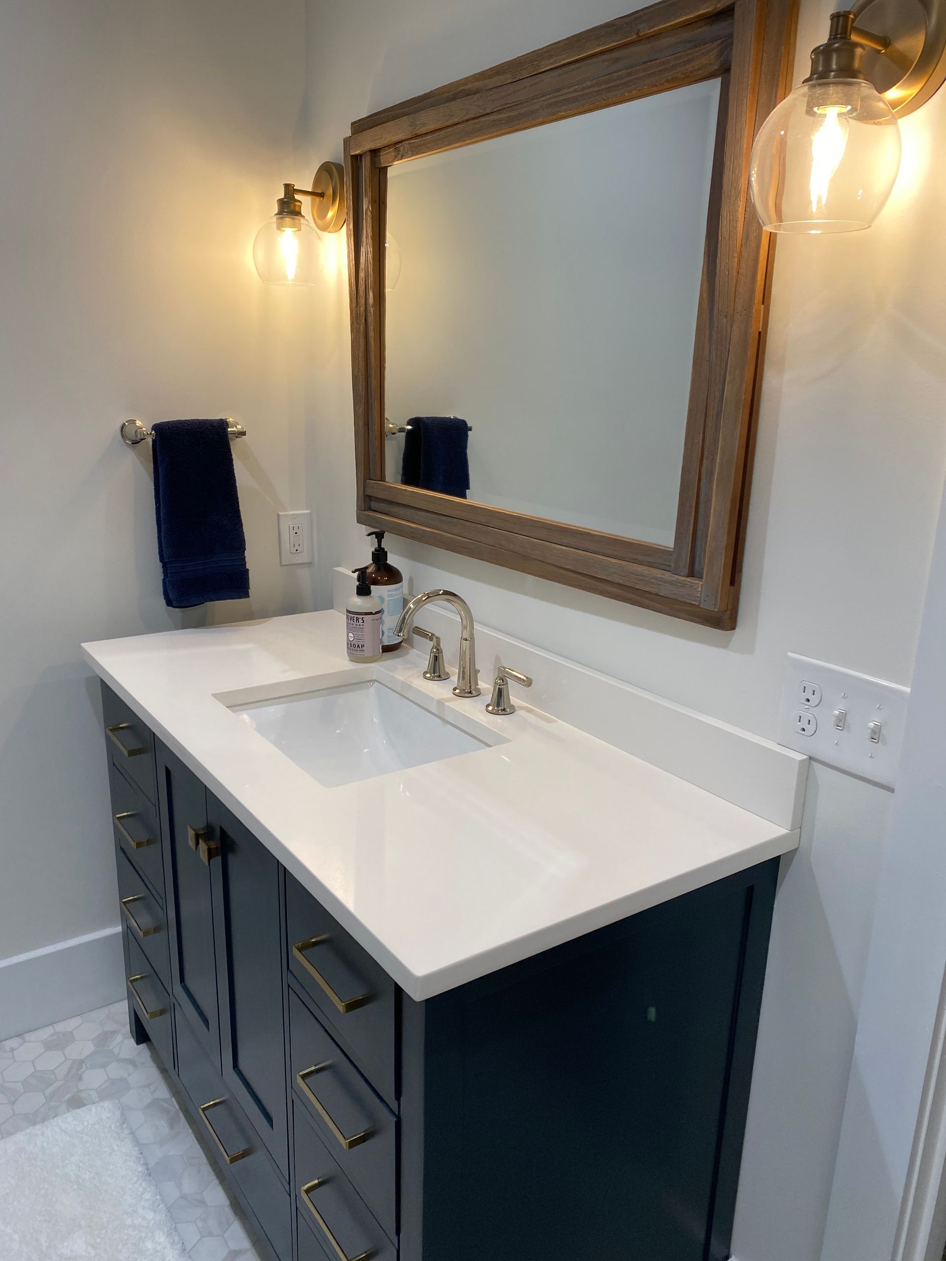 A bathroom with a sink , mirror and towel rack.