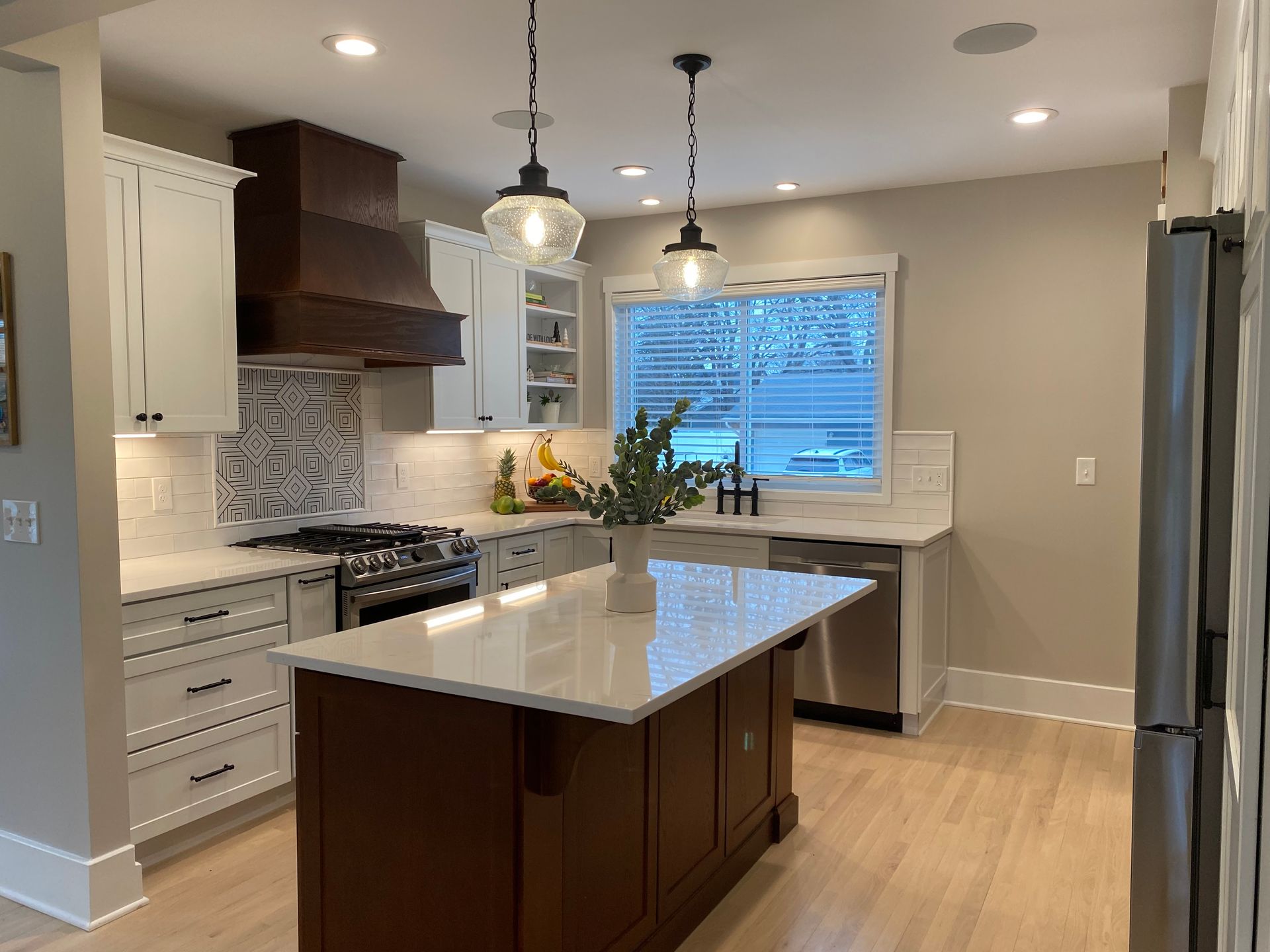 A kitchen with white cabinets , stainless steel appliances , and a large island.