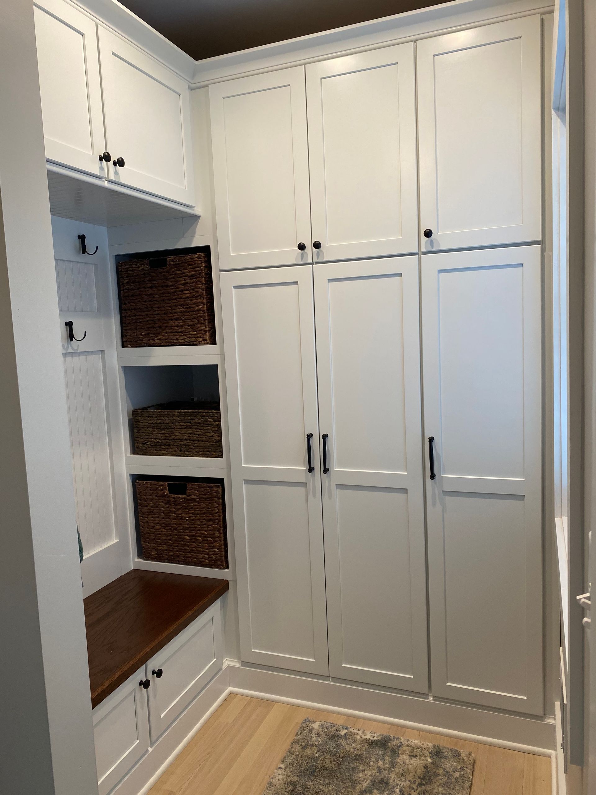 A room with white cabinets and wicker baskets on shelves