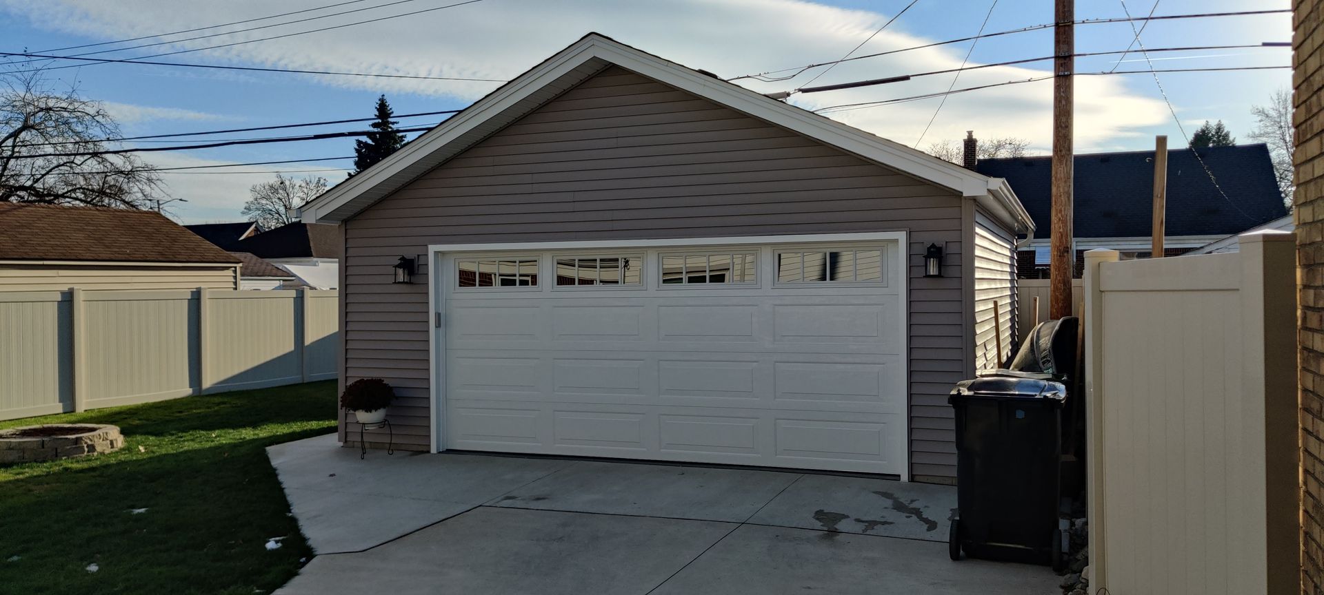 A garage with a white garage door and a white fence