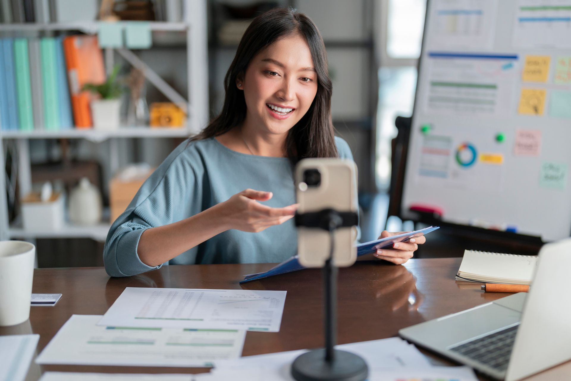 A woman is sitting at a desk using a cell phone.