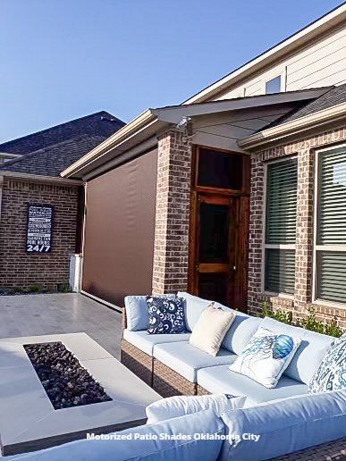 a patio with a couch and a fire pit in front of a brick house with mototirzed patio shades Oklahoma City