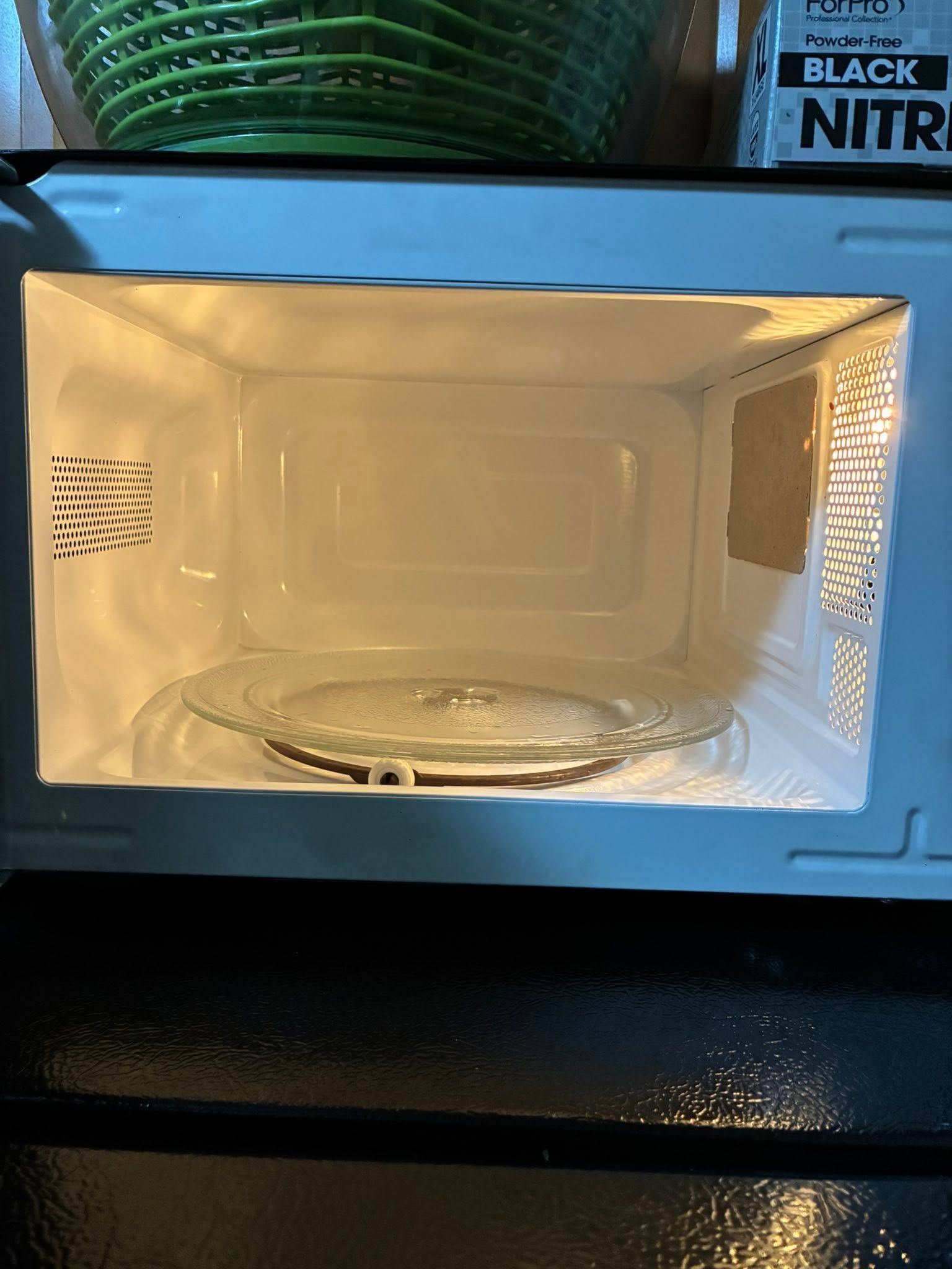 Microwave oven interior with a glass dish on the turntable and blue interior light