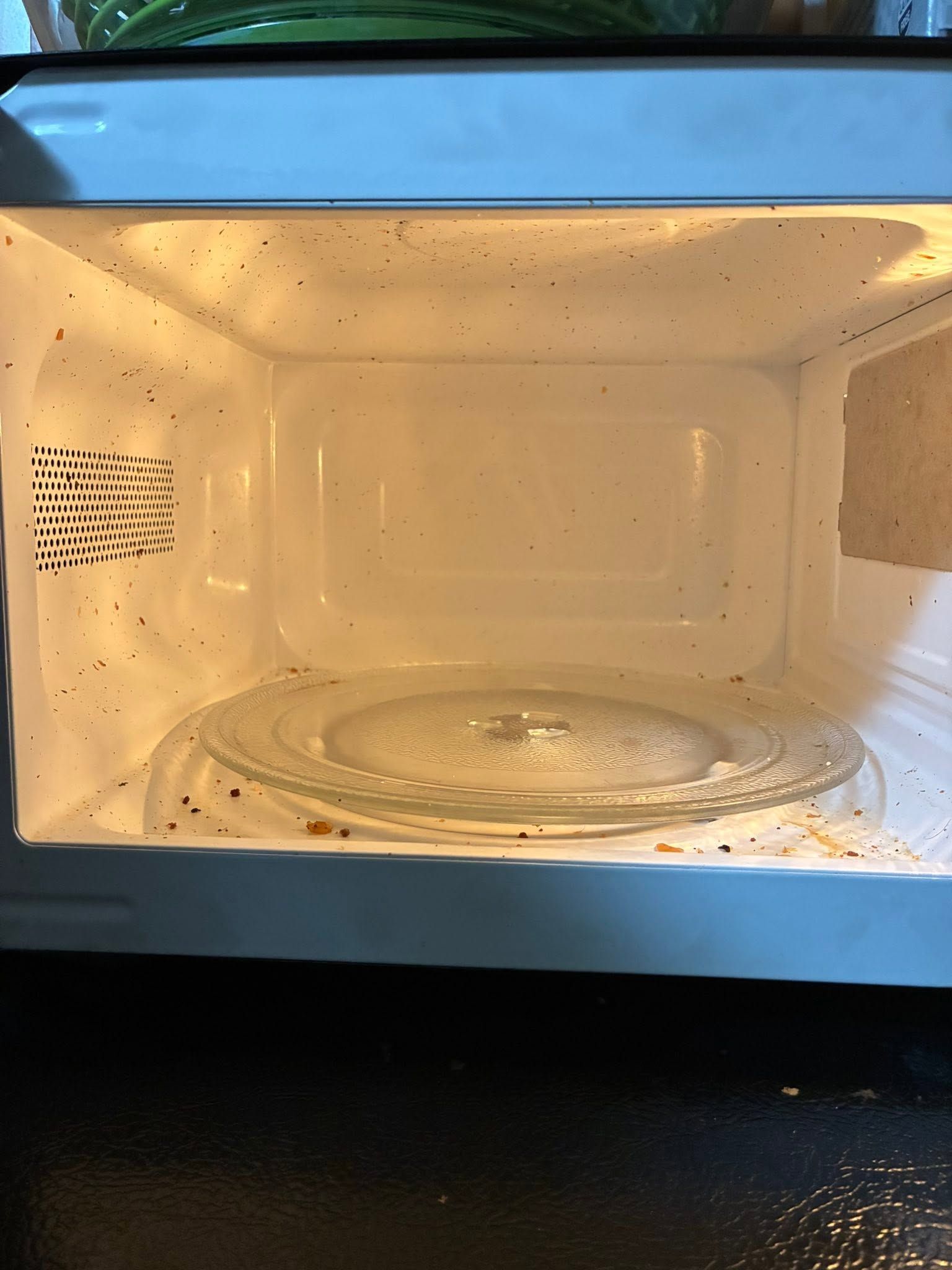 Dirty white microwave interior with splatters and a glass turntable inside.