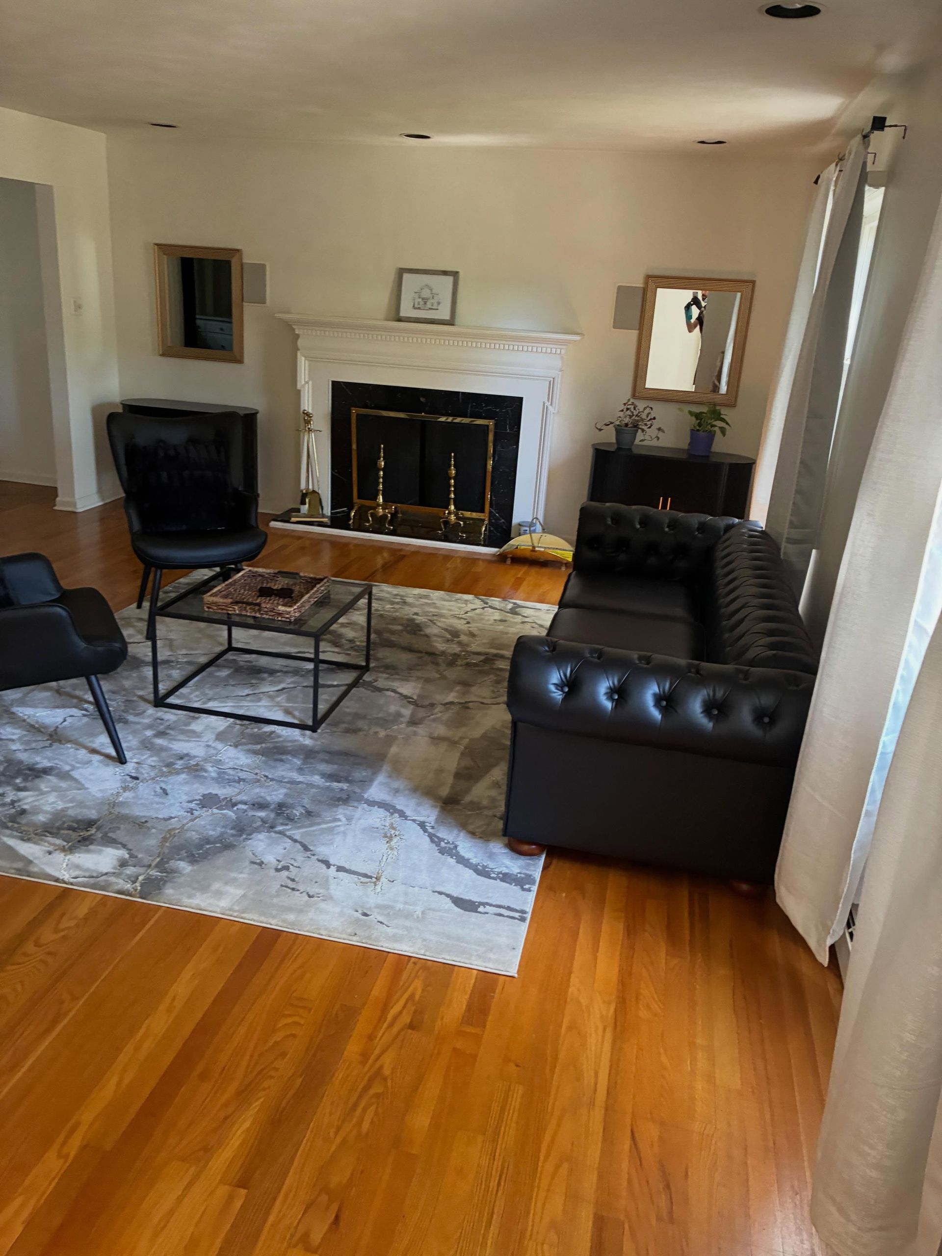 Living room with black leather chairs, fireplace, rug, and hardwood floors