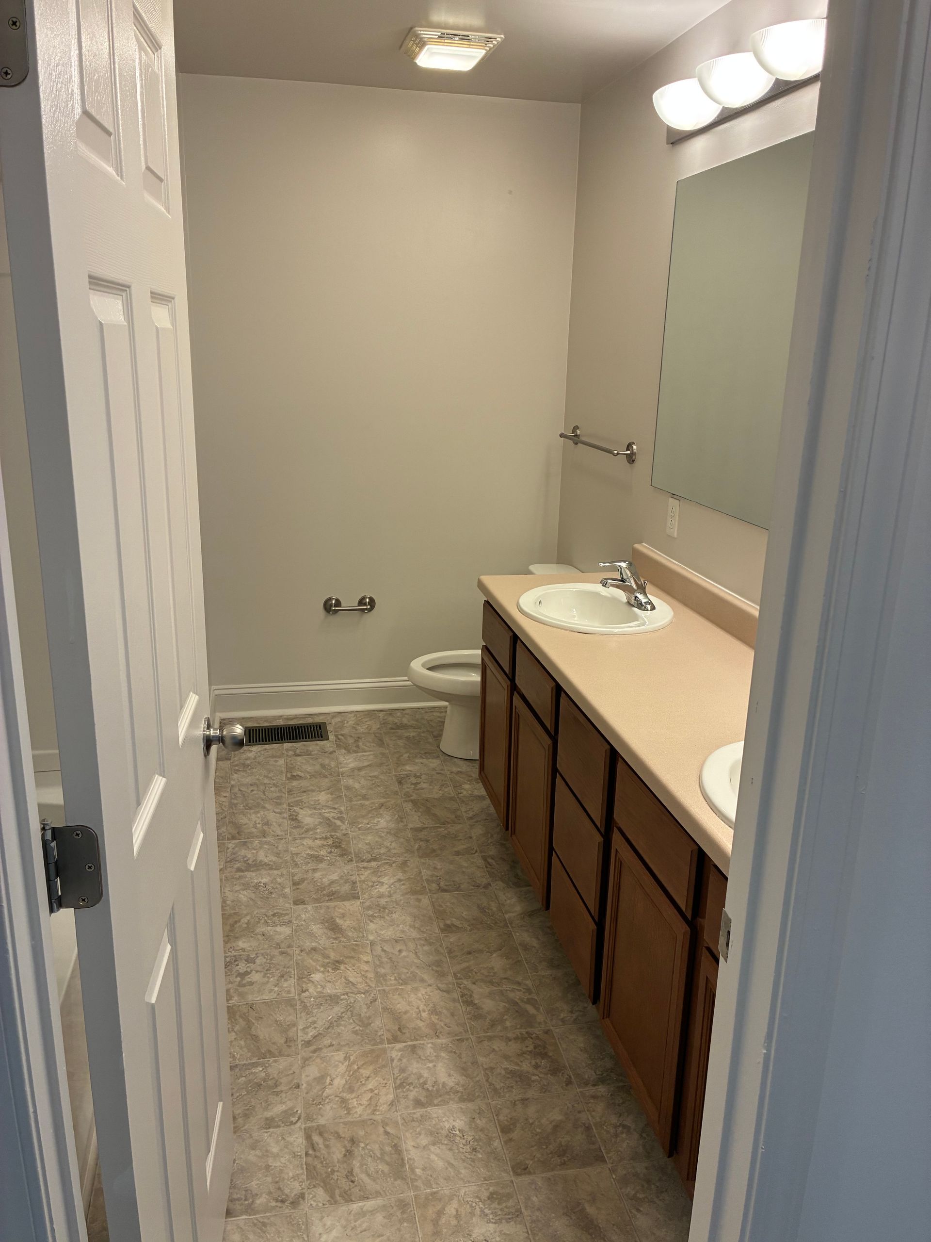 Small bathroom with vanity, sink, toilet, and bathtub under bright lights.