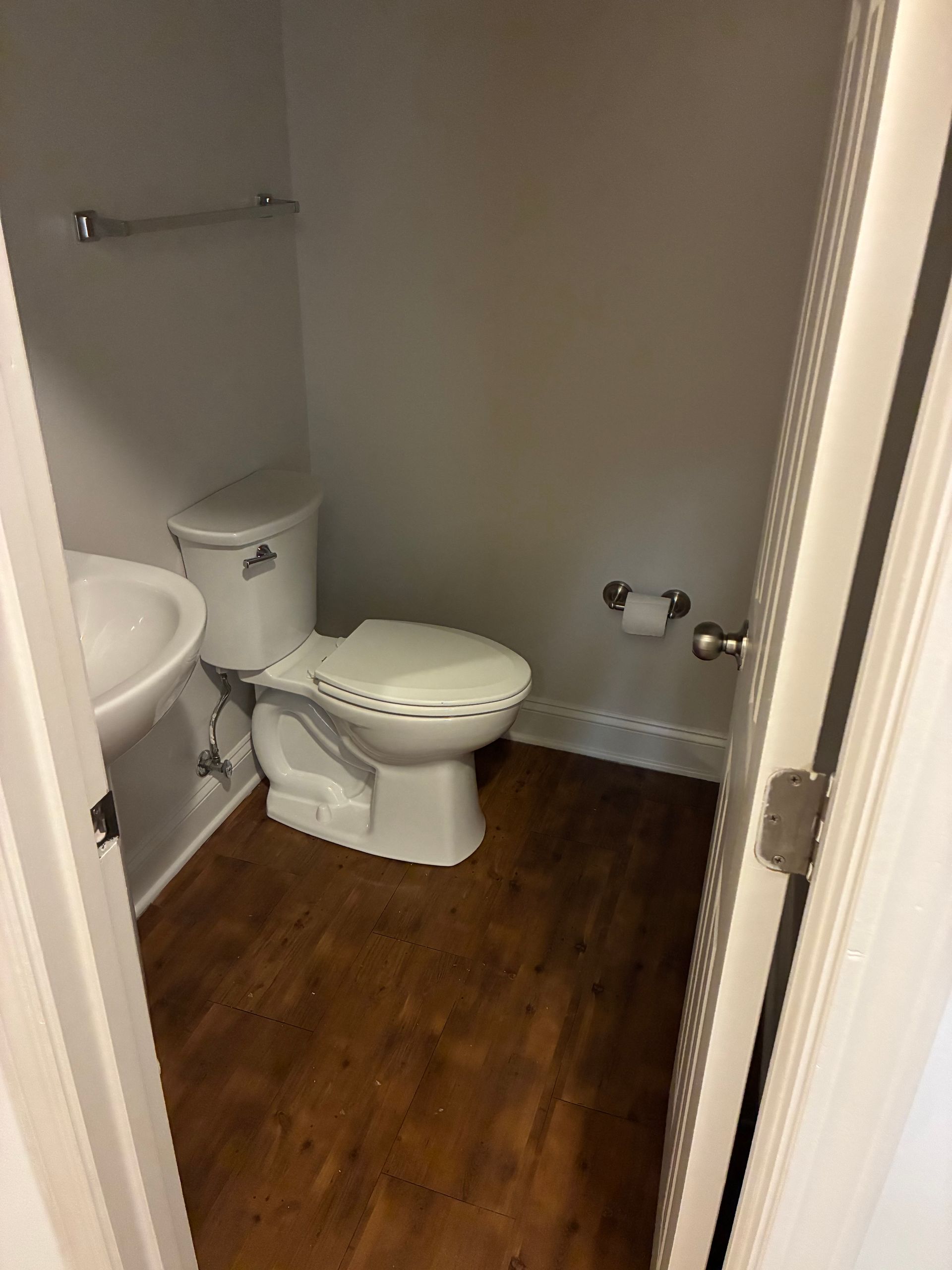 Small bathroom with a toilet, sink, and wood floor.