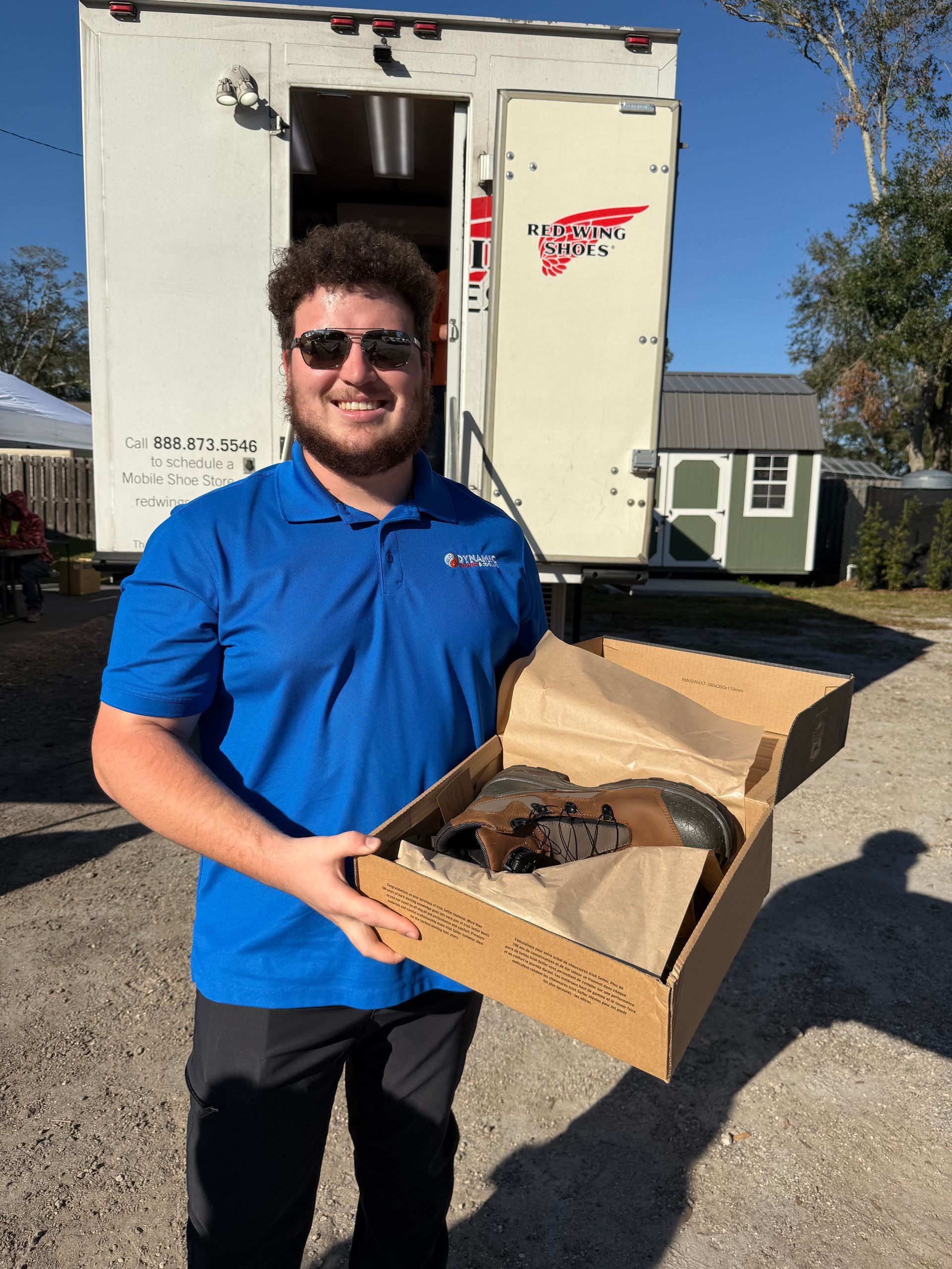 A man in a blue shirt is holding a box of shoes