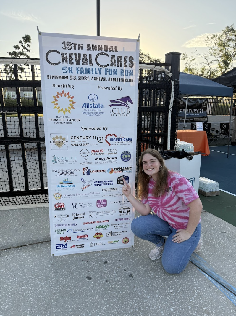 A woman is kneeling down next to a sign that says cheval cares.