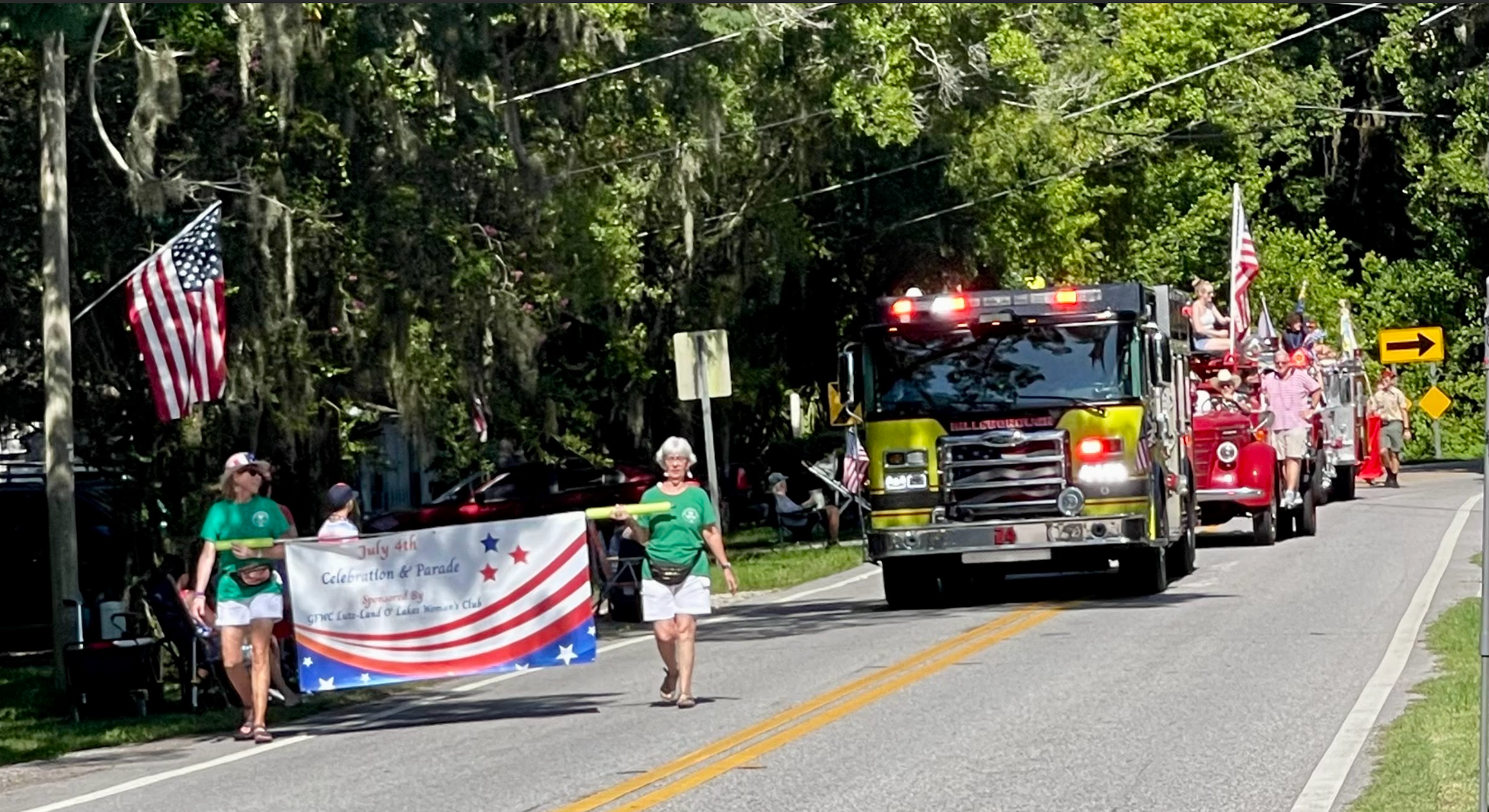 A group of fire trucks are driving down a road in a parade.