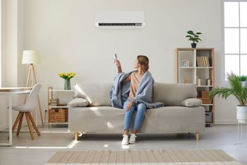 a woman is sitting on a couch in a living room holding a remote control .
