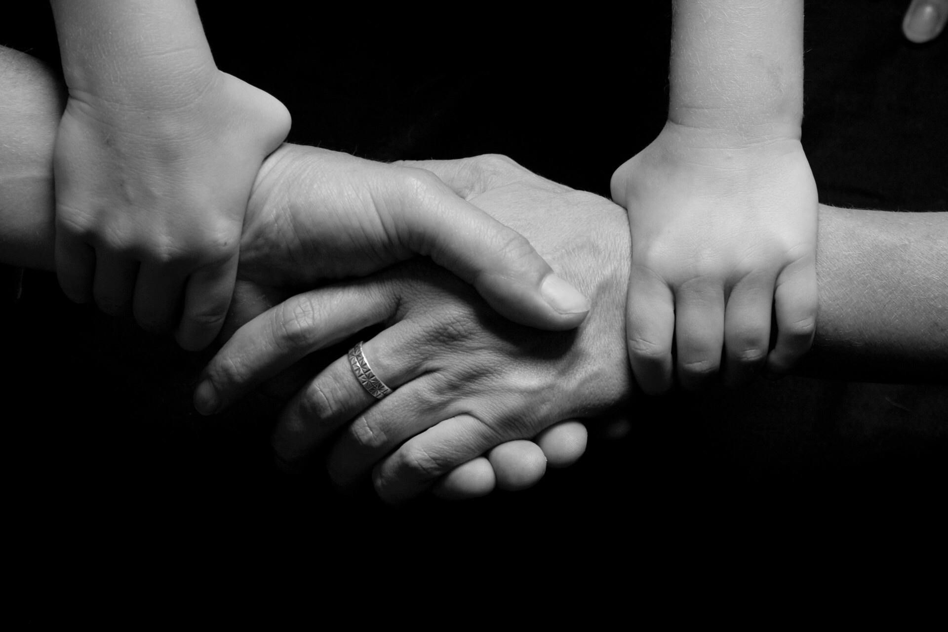 Hands of several people stacked together in a black-and-white close-up, symbolizing teamwork and support