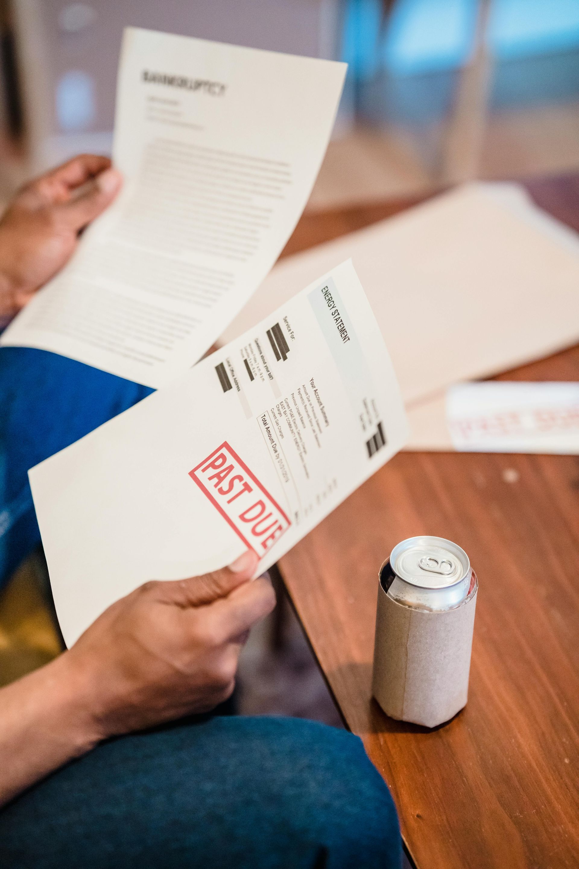 Hands opening a white mail envelope over a table, with a can nearby