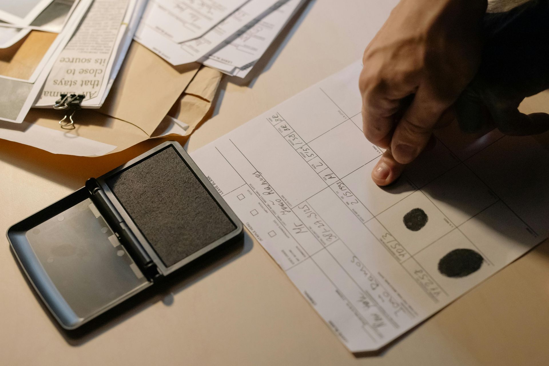 Hand stamping a document on a desk with papers and an ink pad nearby