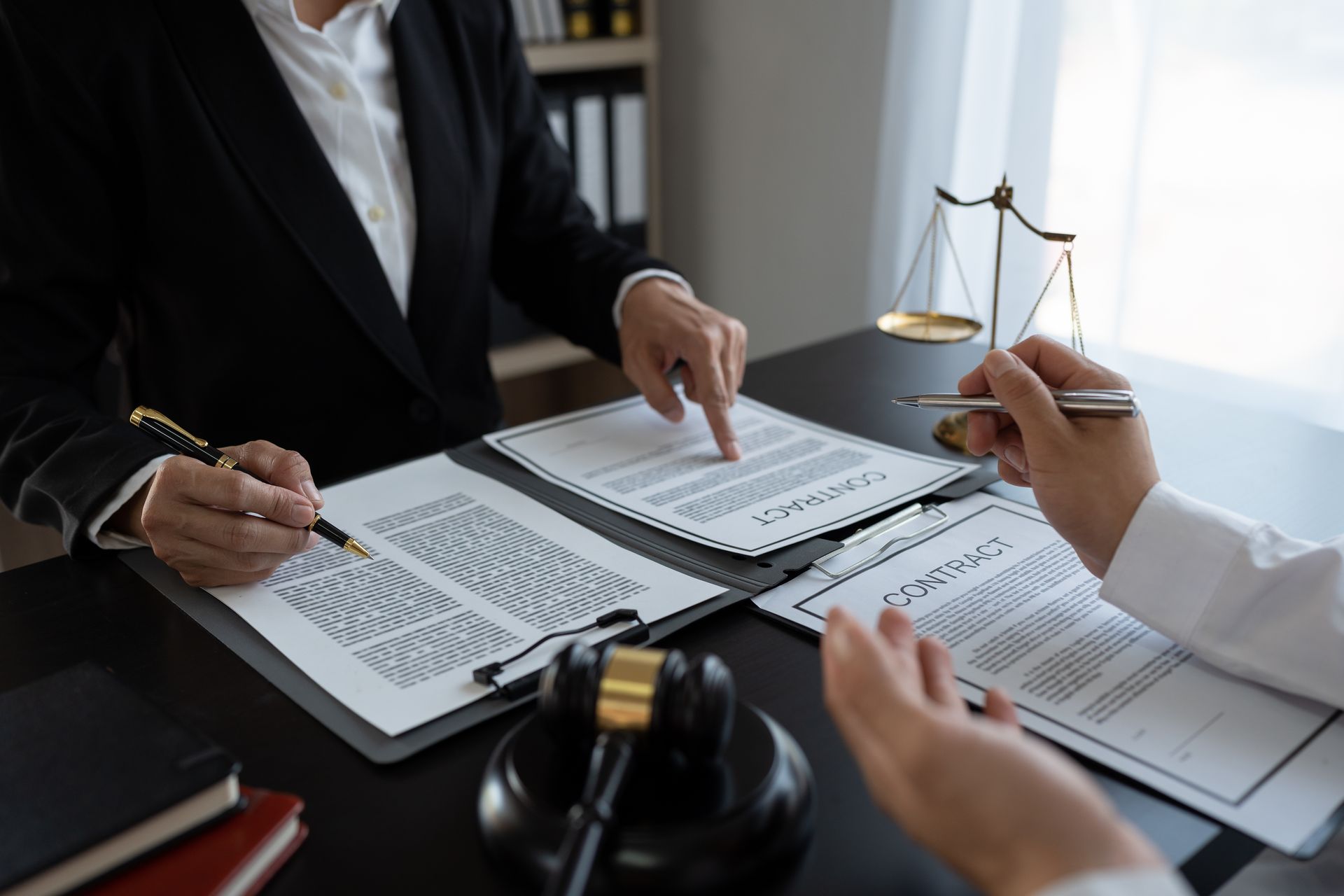 Lawyers reviewing documents at a desk with a gavel and scales of justice