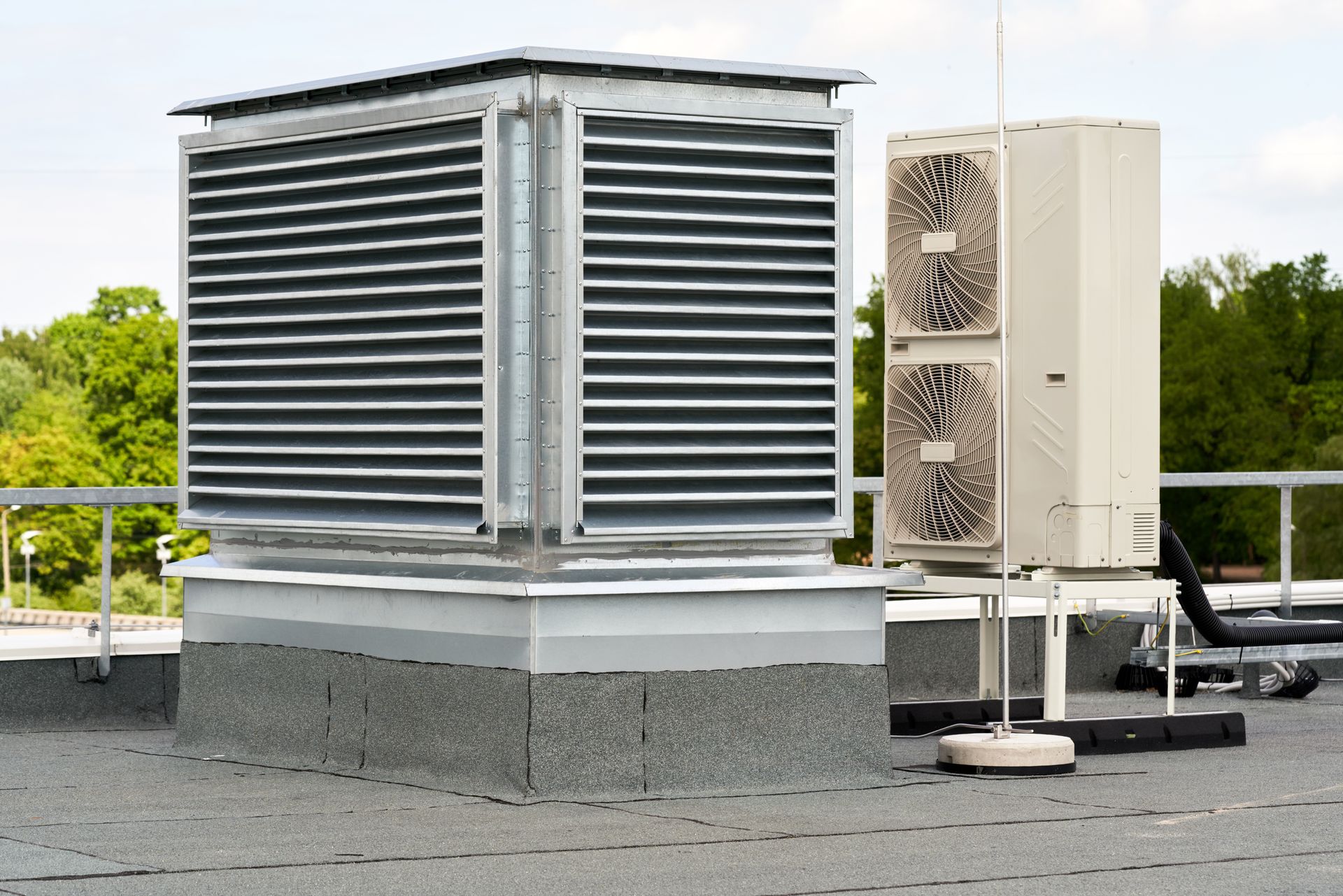 Person in orange work clothes kneeling on a white RV roof, working on an AC unit.