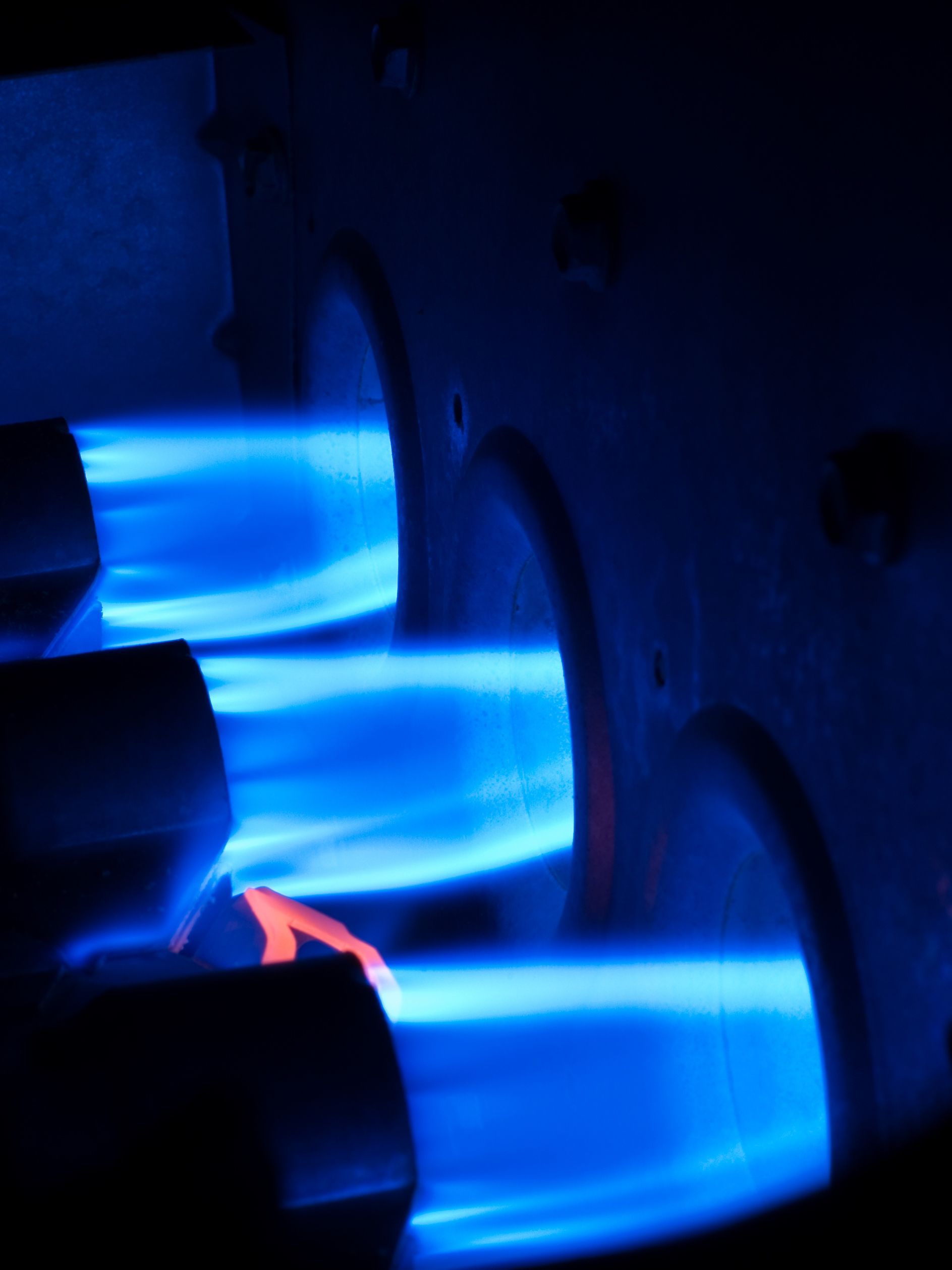 Person inspecting boiler with a device, wearing red gloves.