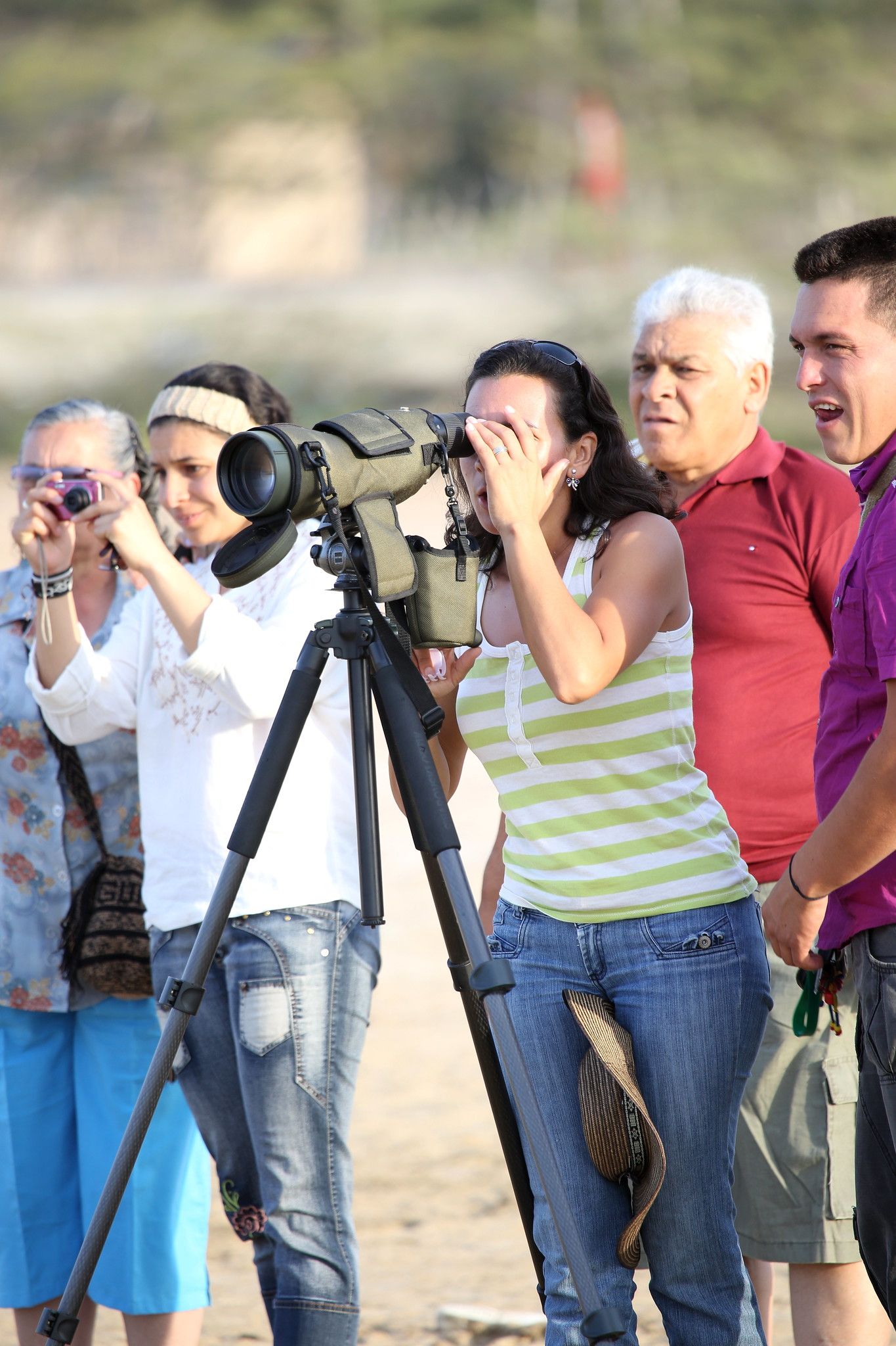 Photographers standing with cameras and a tripod outdoors, aiming toward an event or scene