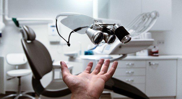A dentist’s office with a hand reaching out towards the chair.