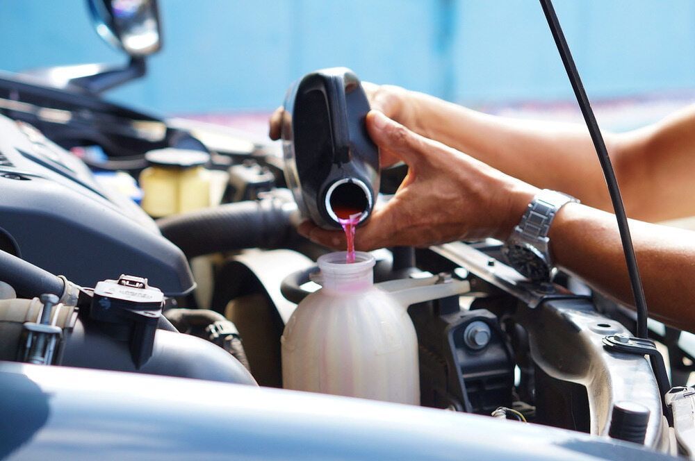 A Person is Pouring Coolant Into a Reservoir — Radiator Doctor In Pialba, QLD