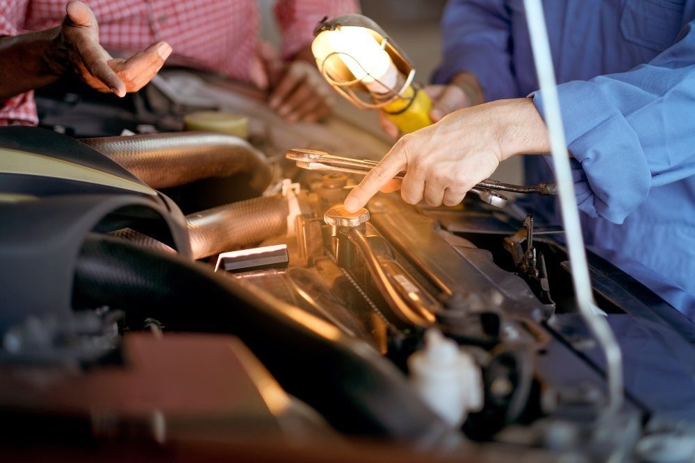 A Man Is Working on A Car Engine with A Light Bulb — Radiator Doctor In Pialba, QLD