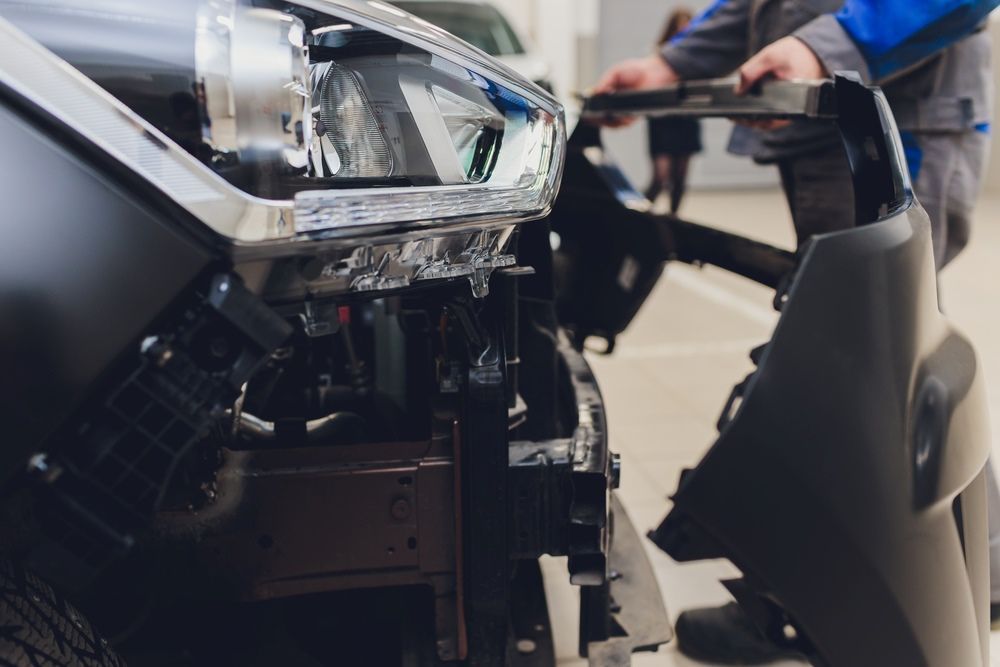 A Man Is Working on The Front of A Car in A Garage — Radiator Doctor In Pialba, QLD