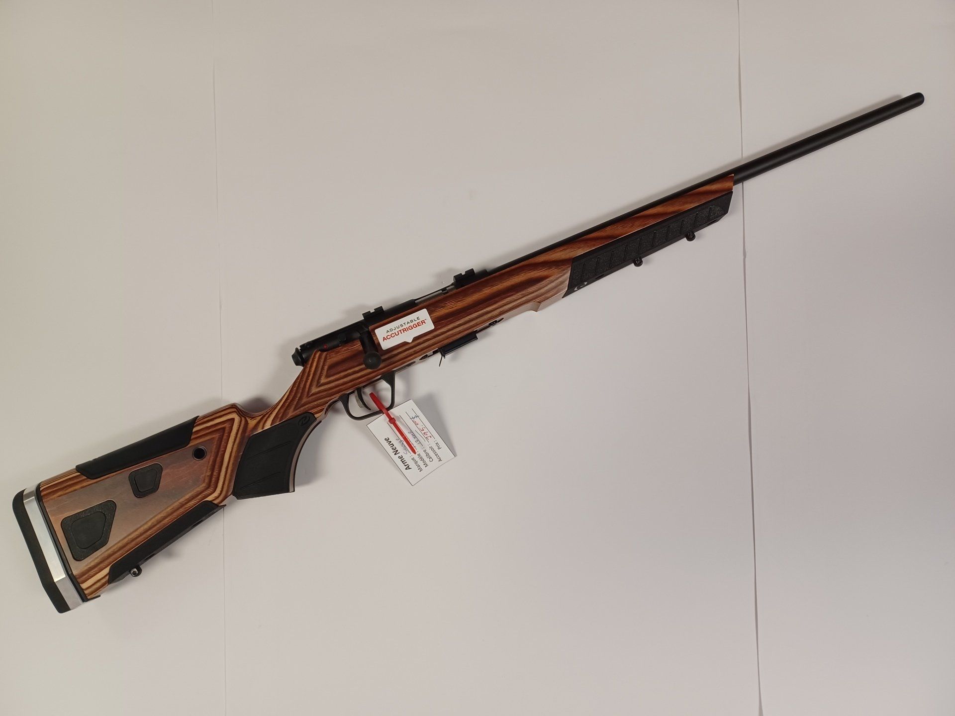 Fusil Savage Axis II avec crosse en bois, canon et action noirs, incliné sur une surface blanche.