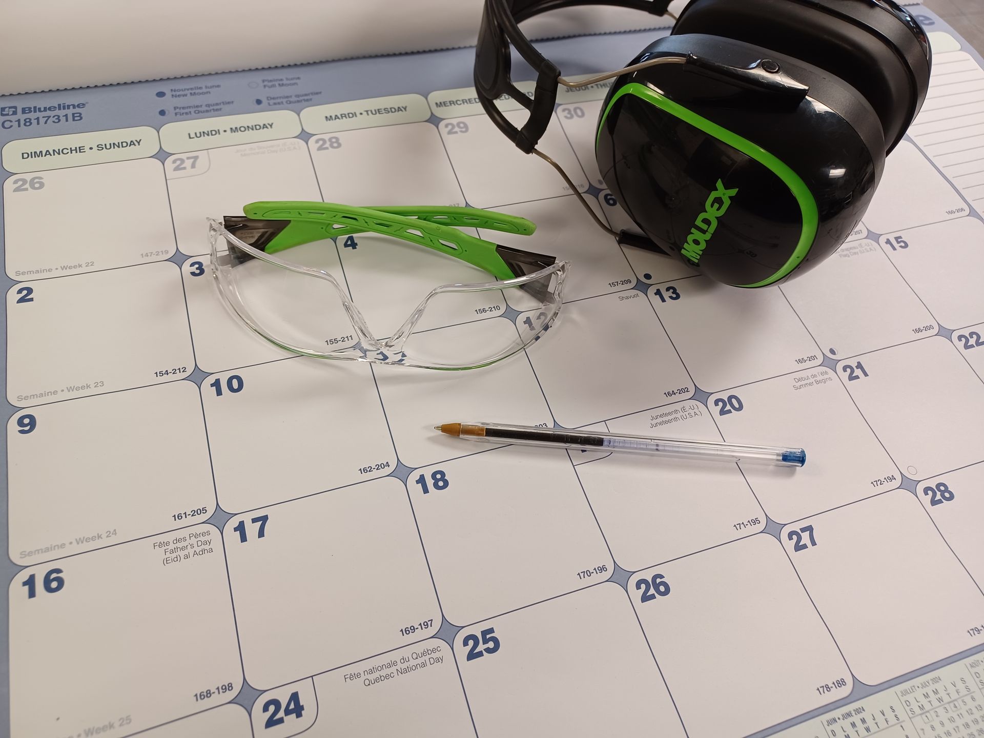 Lunettes de sécurité, casque et stylo sur un calendrier.