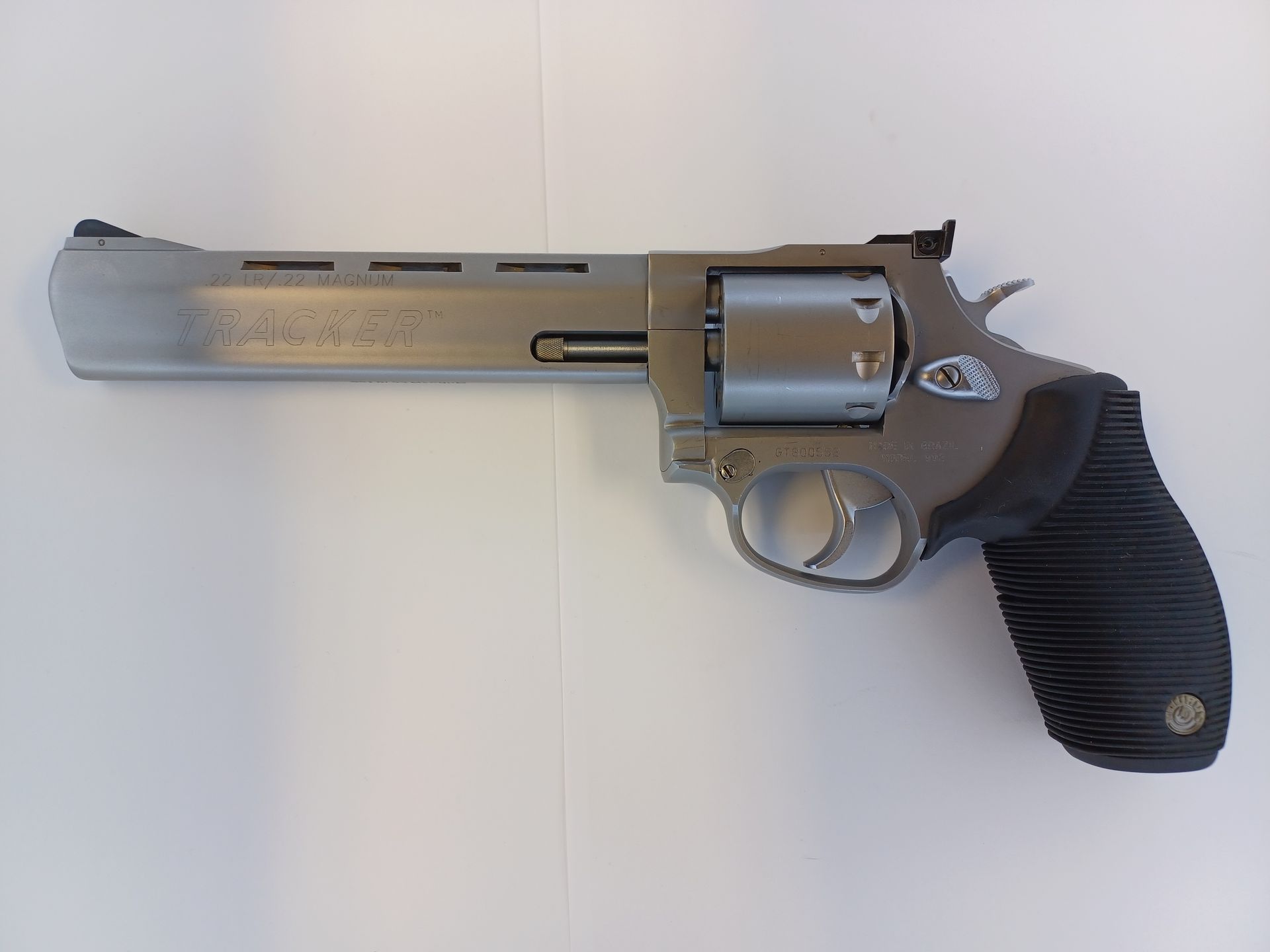 Revolver Taurus argenté à poignée noire, reposant sur une surface blanche.