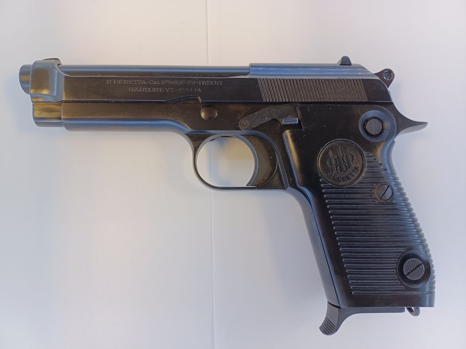 Pistolet Beretta 1935 noir, vue de profil. Acier bleui, culasse nervurée, plaquettes quadrillées.