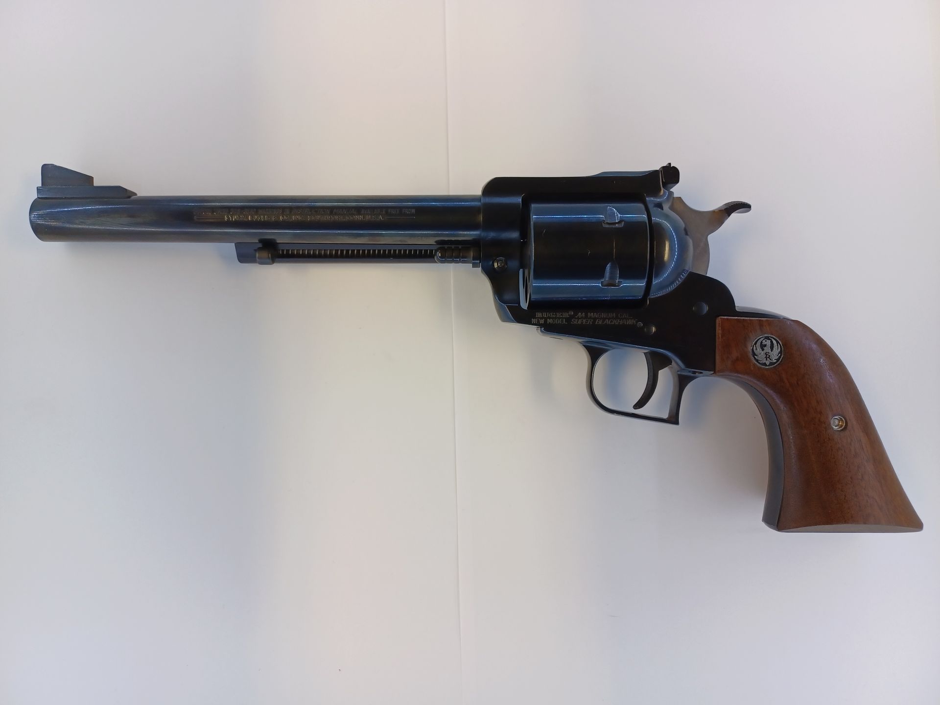 Revolver noir avec poignée en bois marron sur une surface blanche.