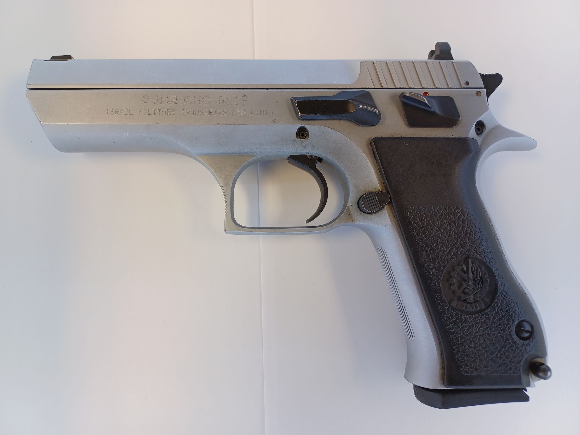 Pistolet argenté et noir sur une surface blanche.