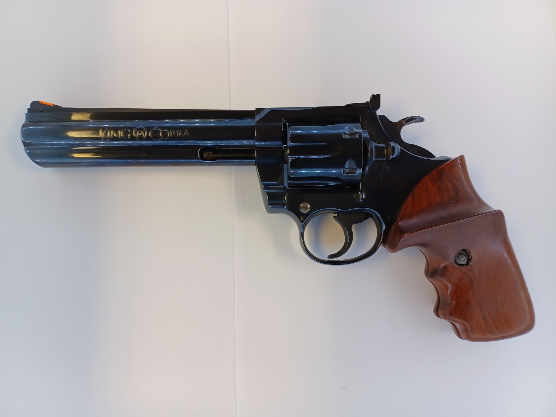 Revolver noir avec poignée en bois sur fond blanc.