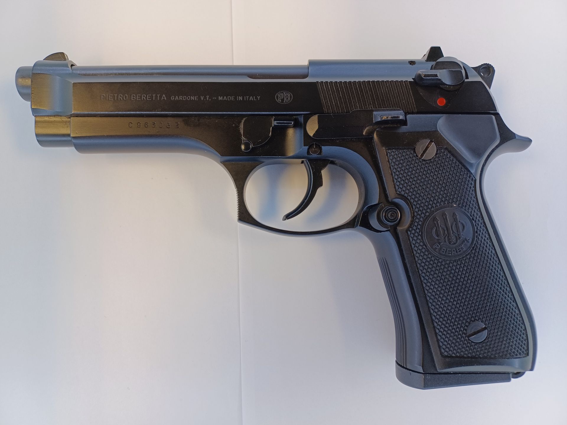 Pistolet Beretta 92 noir sur une surface blanche.