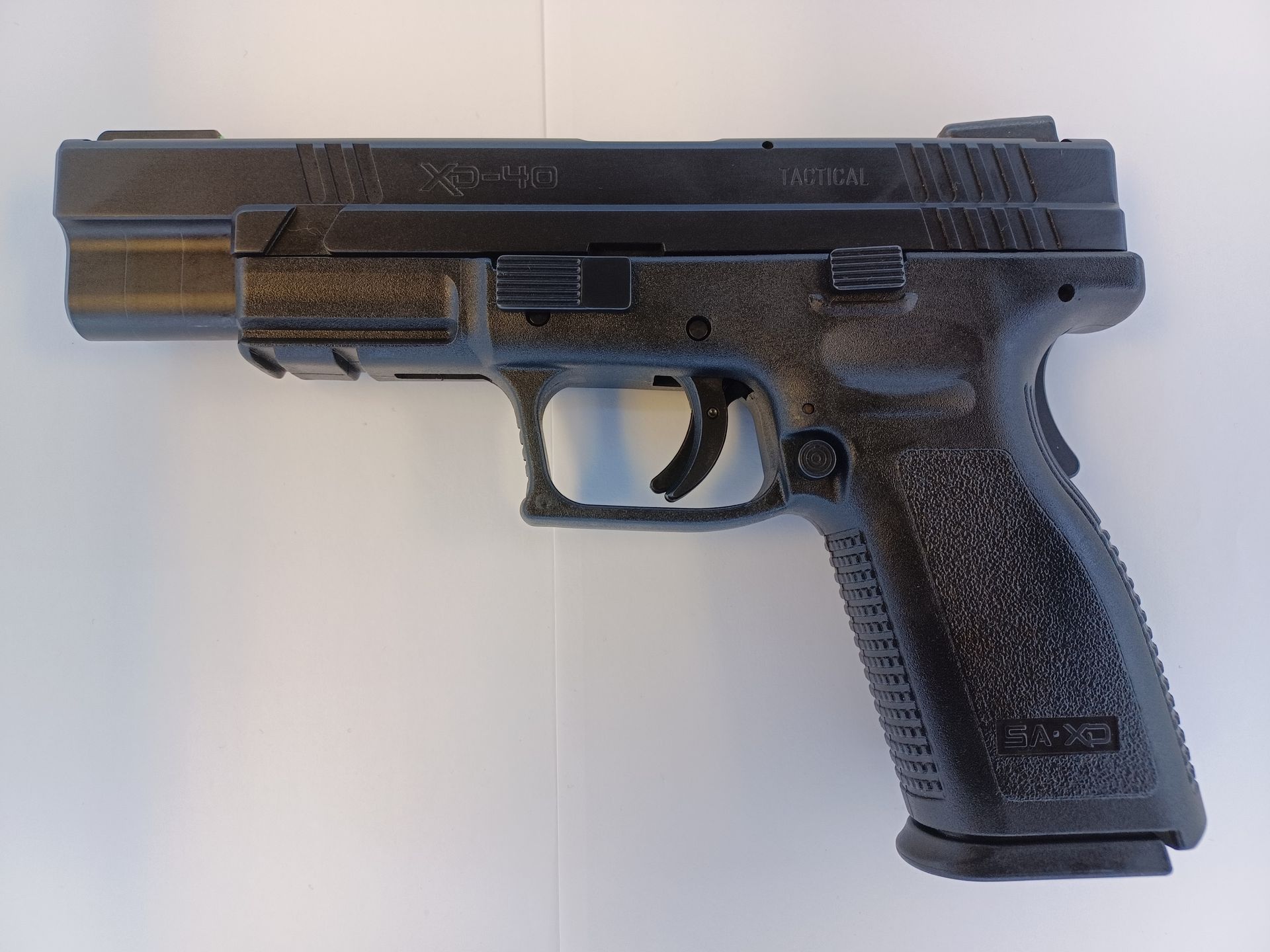 Pistolet noir sur une surface blanche ; arme à feu.