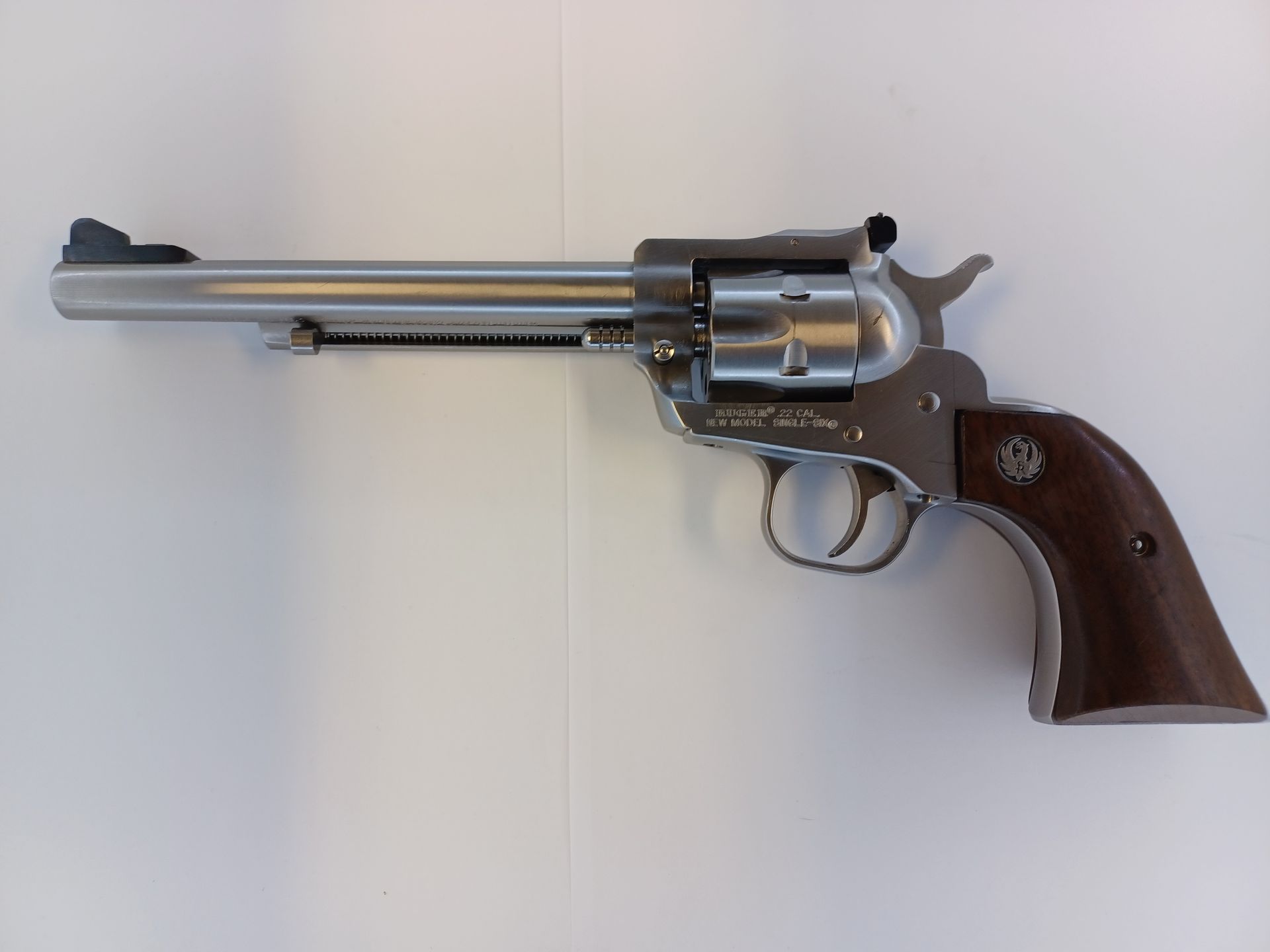 Revolver Ruger argenté avec poignée en bois sur une surface blanche.