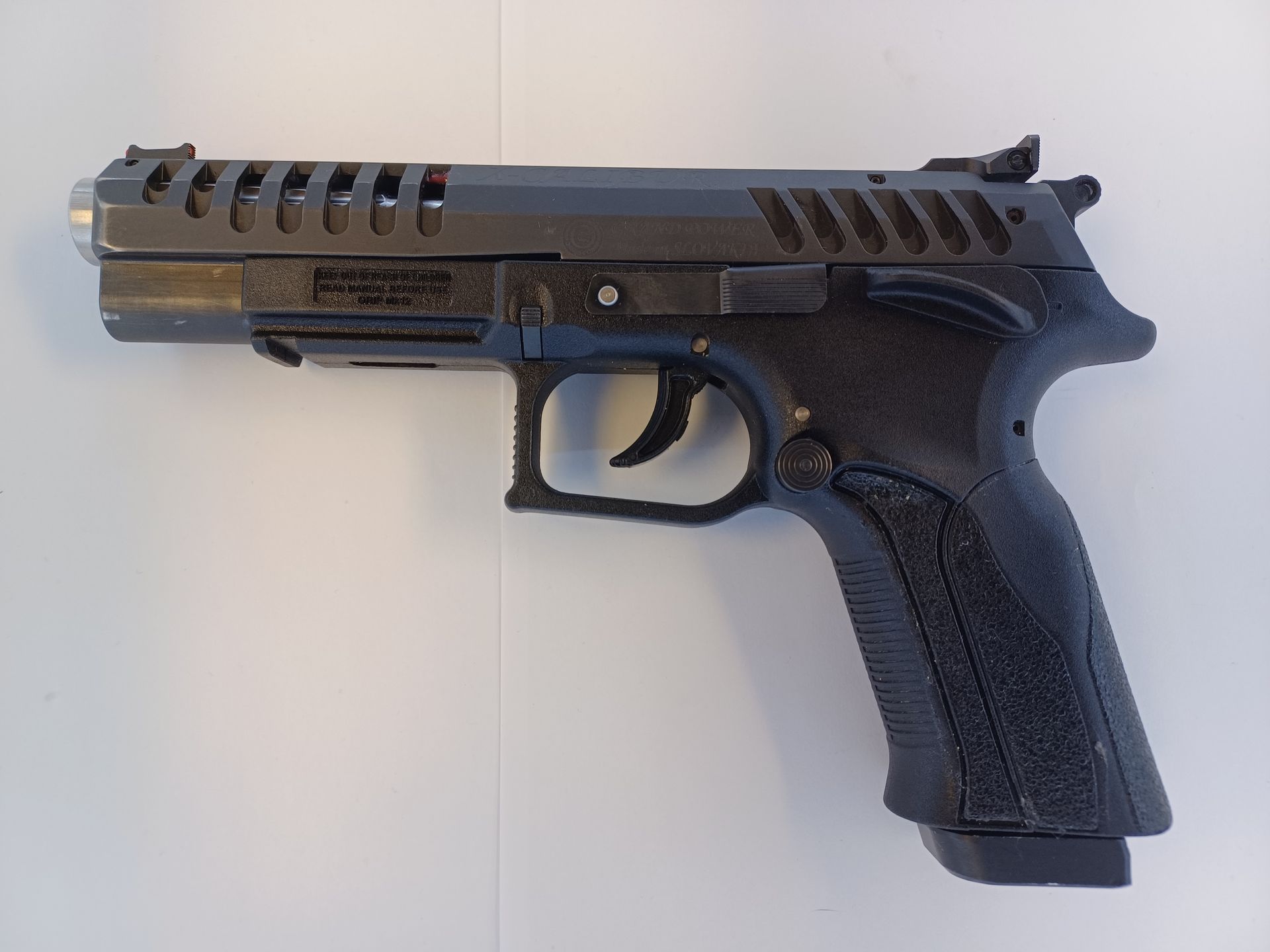 Pistolet noir sur fond blanc. Le pistolet est doté d'une poignée texturée et d'une glissière ventilée.