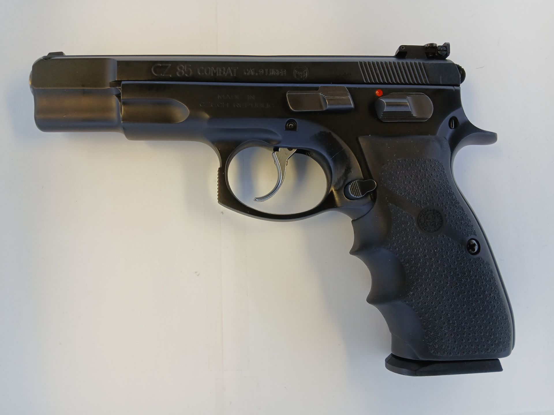 Pistolet CZ 75 noir sur fond blanc, montrant le profil latéral avec une poignée texturée et des viseurs.
