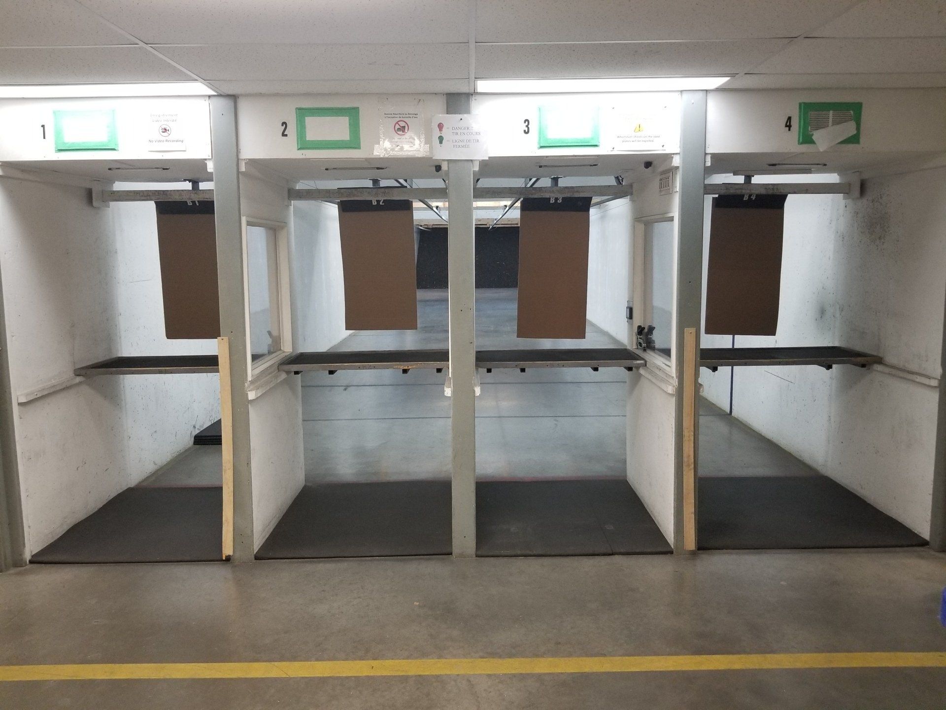 Stand de tir vide avec stands numérotés, toiles de fond pour cibles et sols en béton.